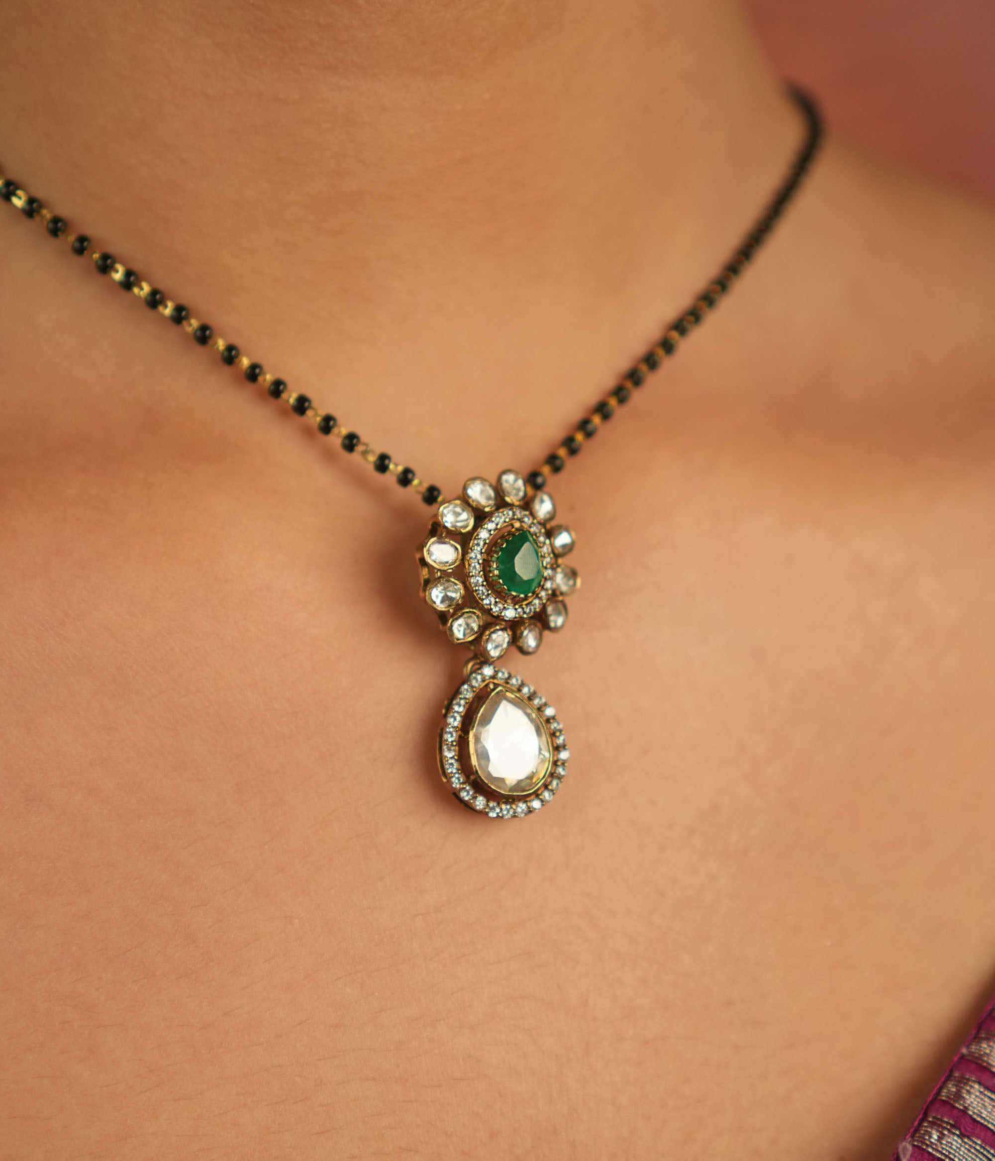 An enchanting floral pendant adorned with Moissanite Polki stones and a vibrant green gemstone at its heart, encircled by shimmering CZ stones—nature’s grace reborn, a dewdrop of timeless elegance.