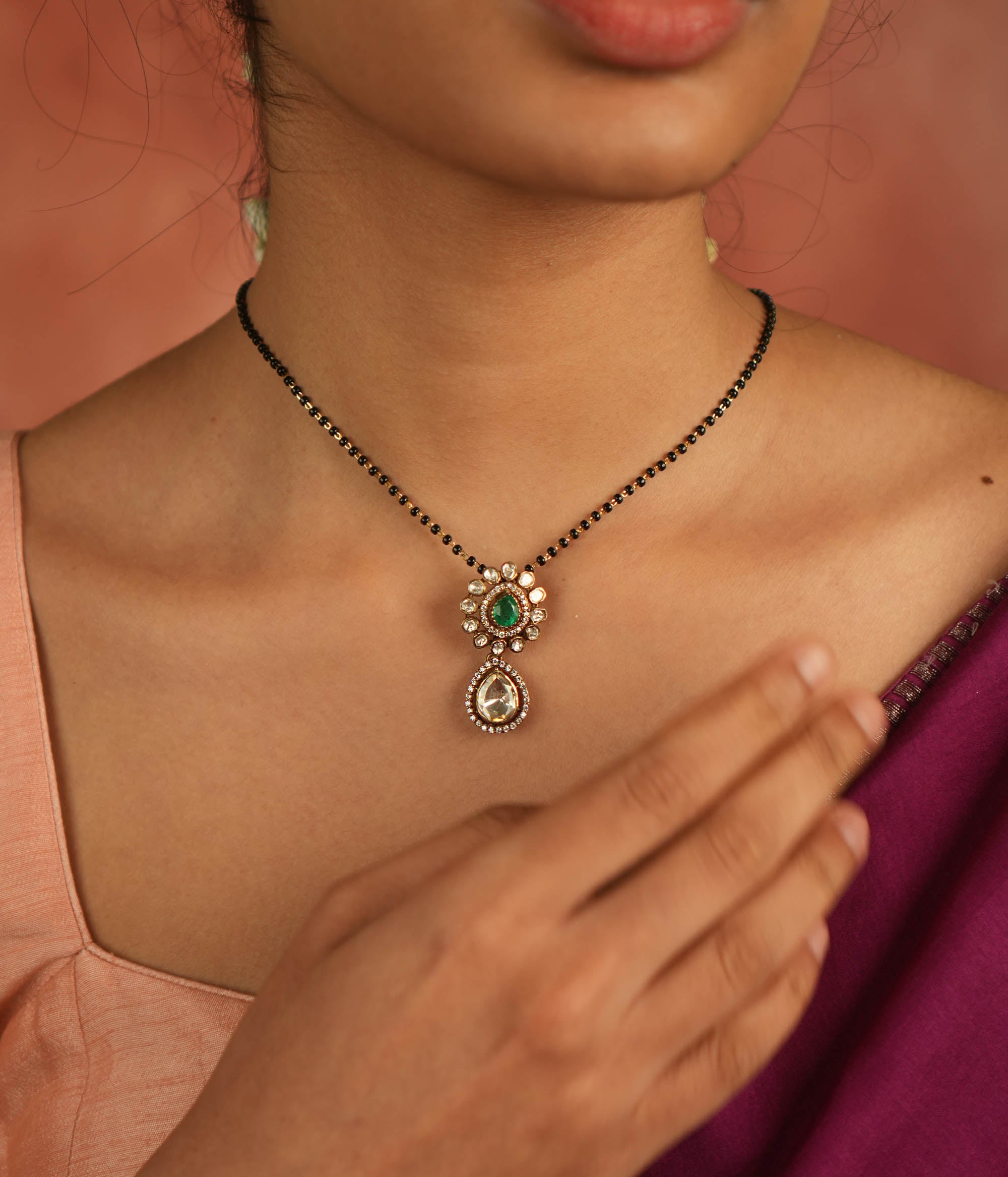 An enchanting floral pendant adorned with Moissanite Polki stones and a vibrant green gemstone at its heart, encircled by shimmering CZ stones—nature’s grace reborn, a dewdrop of timeless elegance.