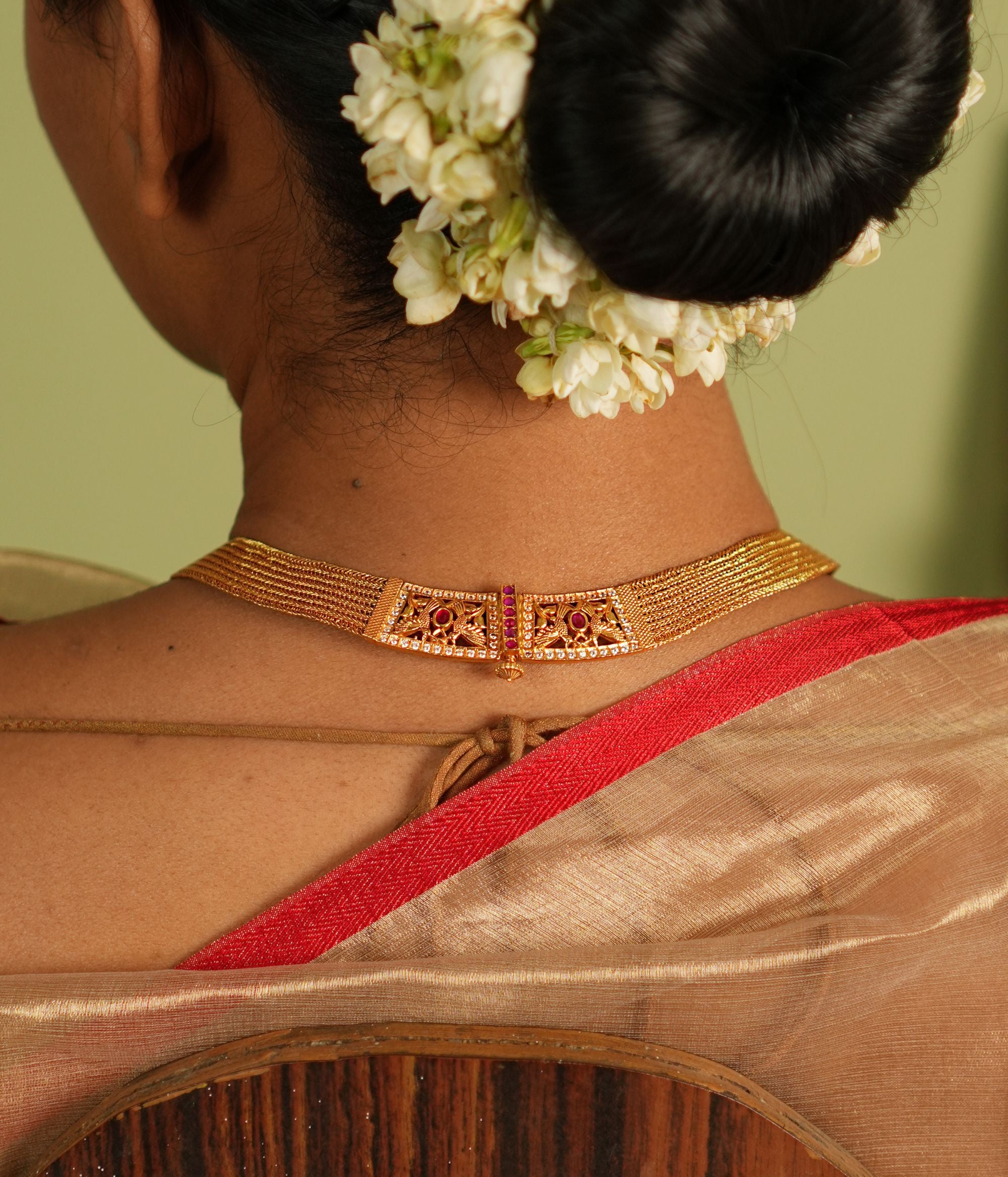 Elegant gold-plated silver necklace featuring a continuous flat-structured chain with a secure screw closure at the end. The design is adorned with intricate tiny peacock motifs, embellished with vibrant red Kundan stones and shimmering CZ stones, adding a touch of traditional grace and sophistication.