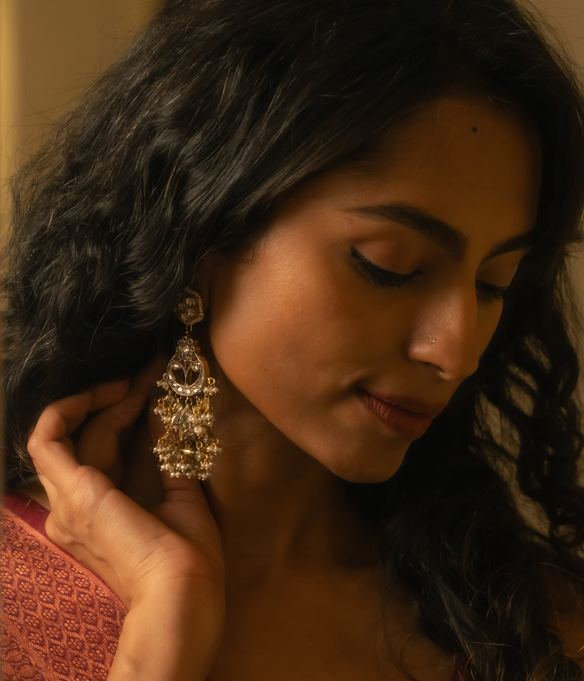 Woman wearing ornate gold Taarini earrings with rubies, white sapphires, and pearl danglers.