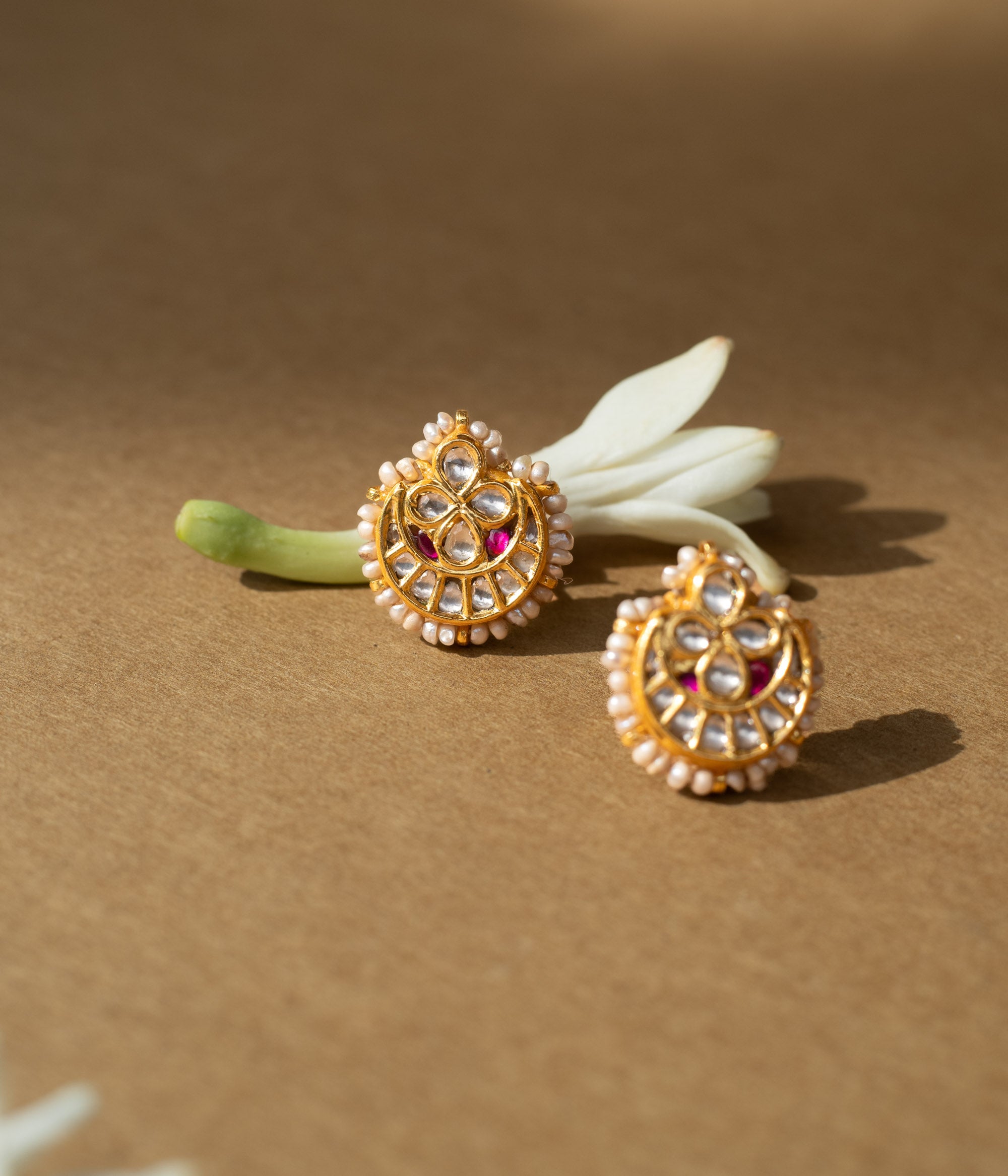 Teardrop-shaped gold earrings with white sapphires, rubies, and a pearl-studded edge.