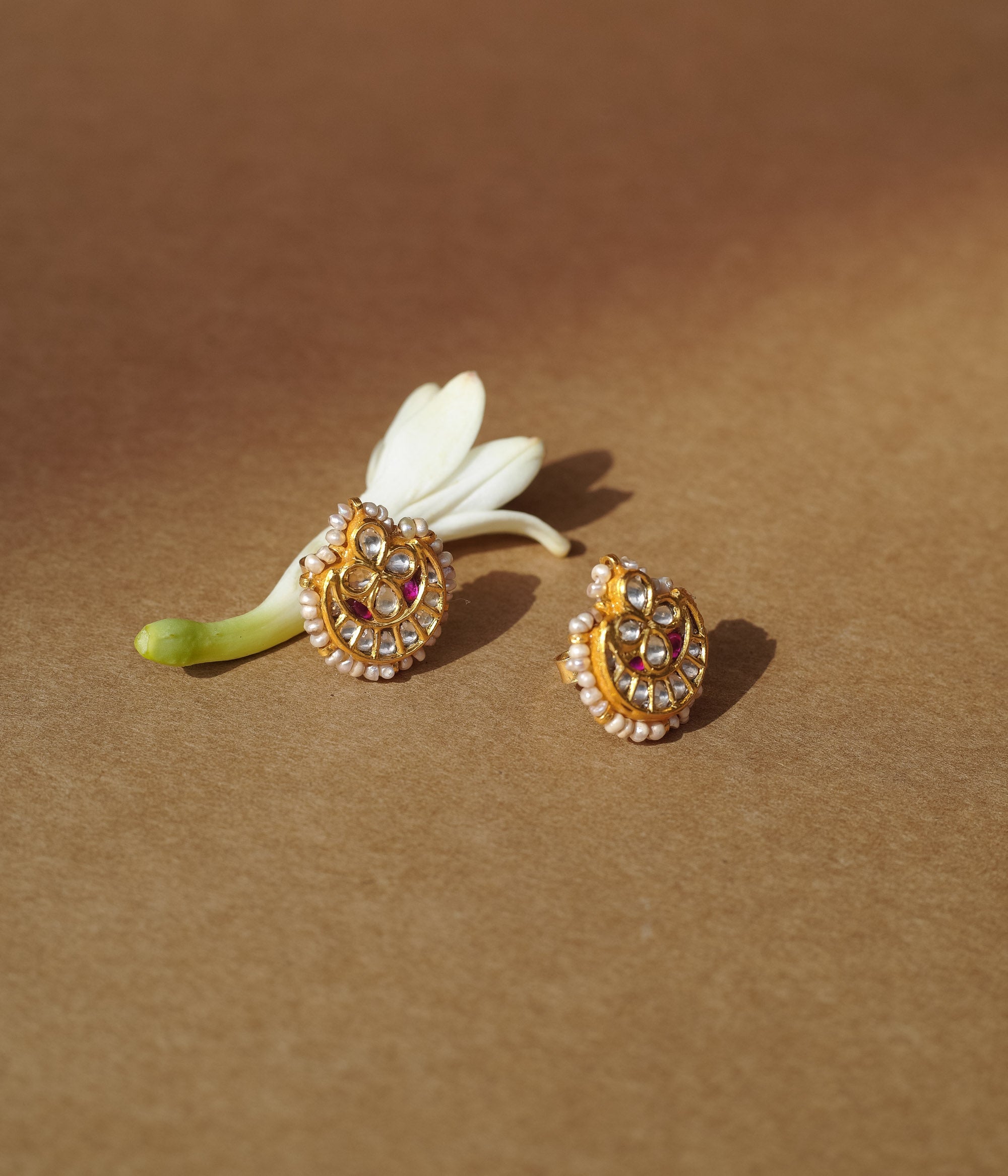 Teardrop-shaped gold earrings with white sapphires, rubies, and a pearl-studded edge.