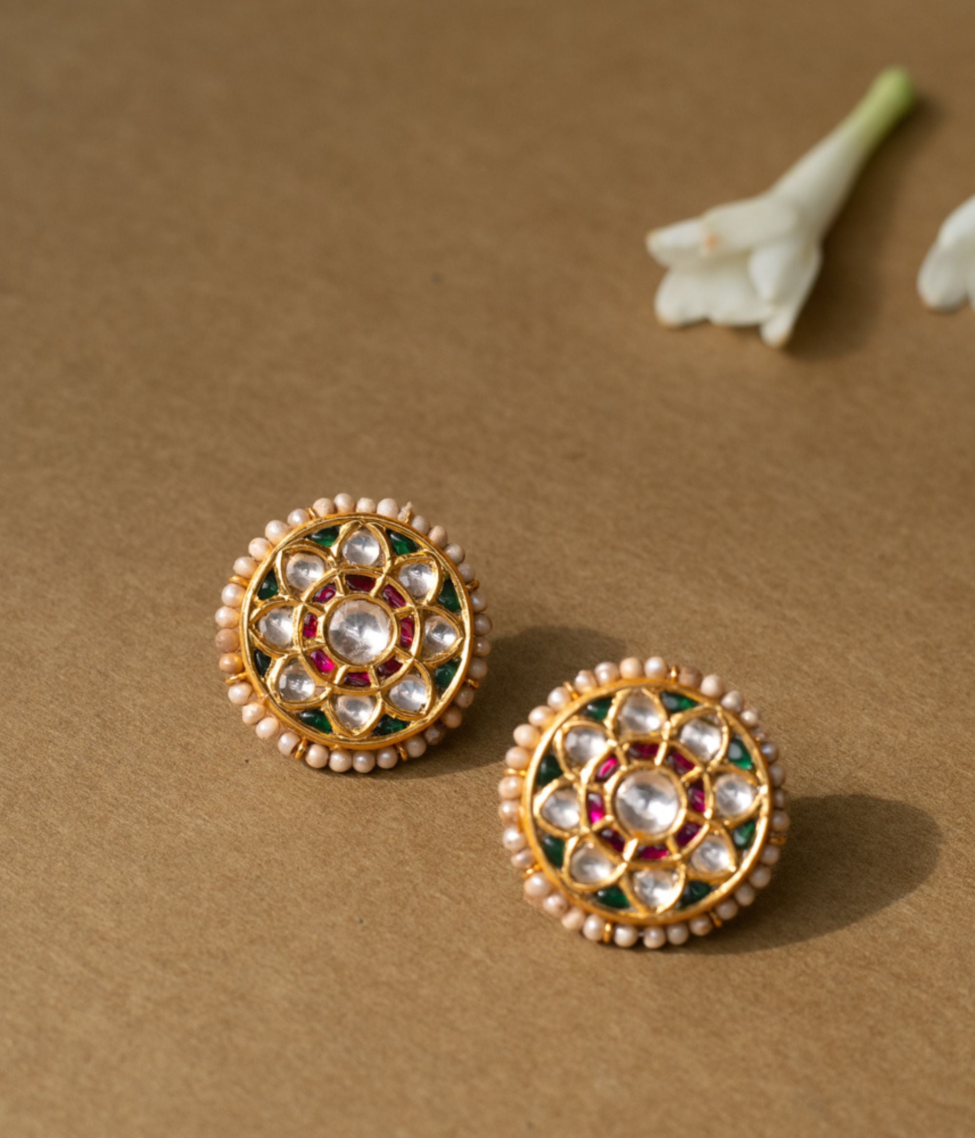 Round lotus-style earrings with white sapphires, rubies, green enamel accents, and pearl border.