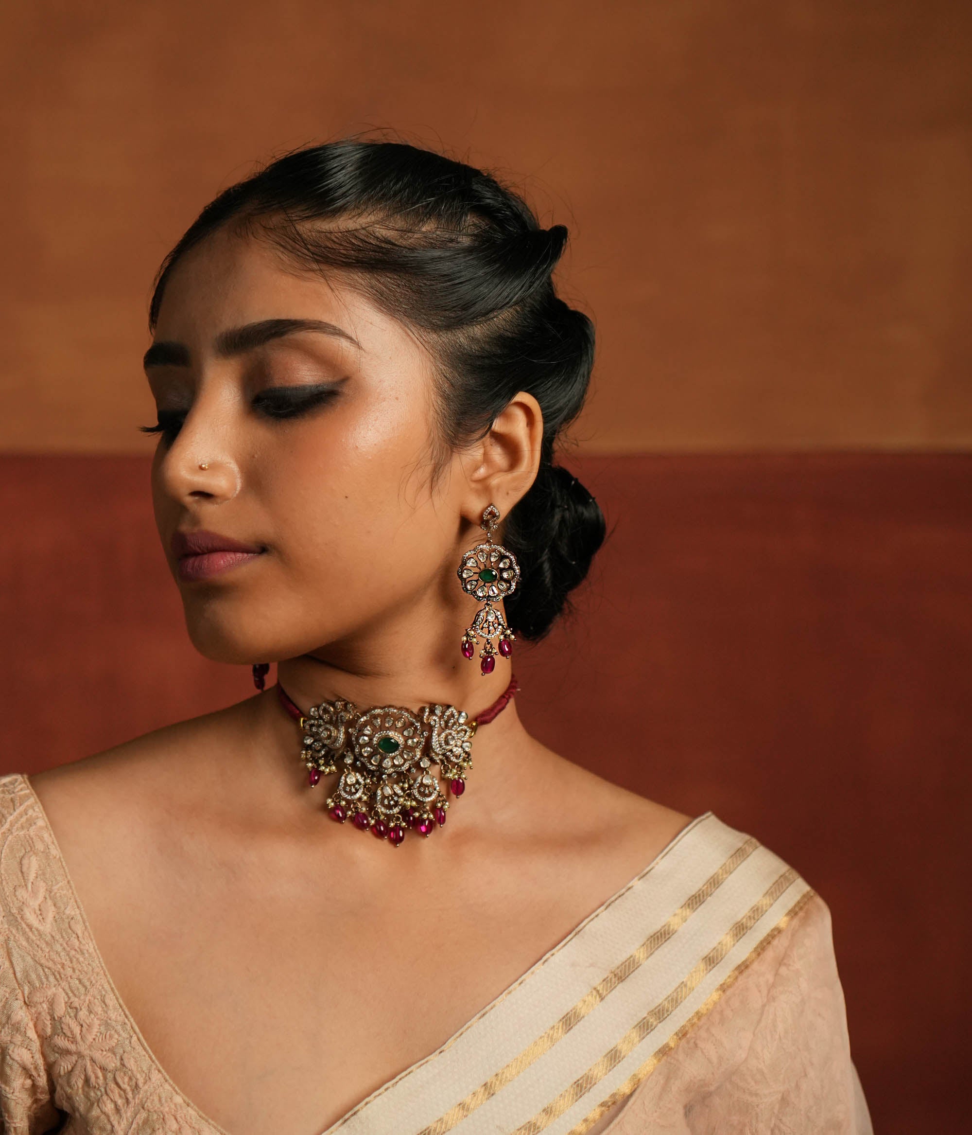 Gold-plated floral dangler earring featuring Green Gemstone, Moissanite Polki Stones, Pearls, Red Beads, and CZ Stones. The earring has a floral design with Polki and CZ stones arranged around it, complemented by delicate drops of red beads for an elegant finish.