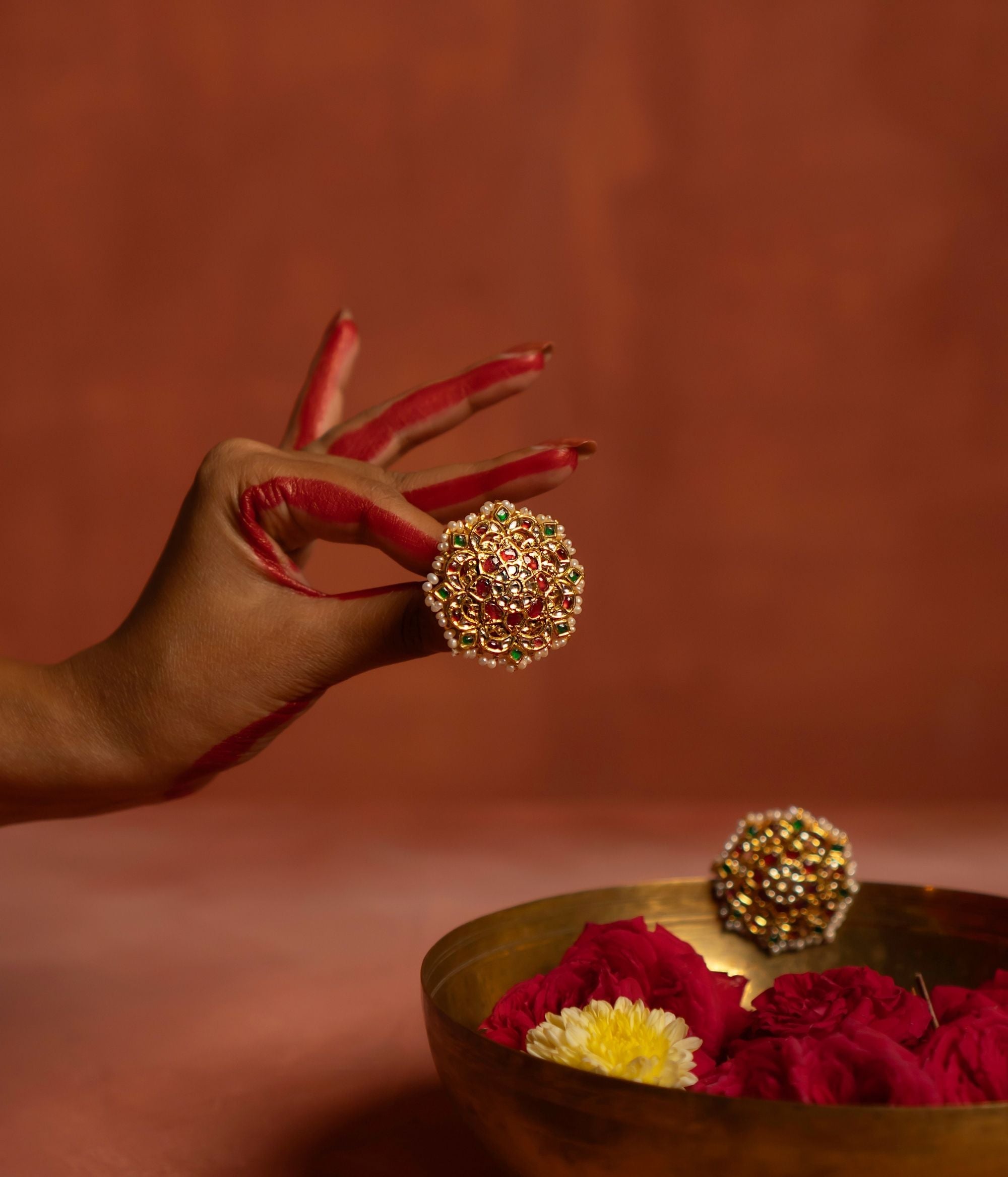 A beautifully crafted gold-plated silver push-type stud earring in a round floral design. Adorned with vibrant rubies, sparkling white sapphires, rich emeralds, and elegant white pearls, this earring exudes a traditional charm, making it a perfect accessory for ethnic and festive occasions.