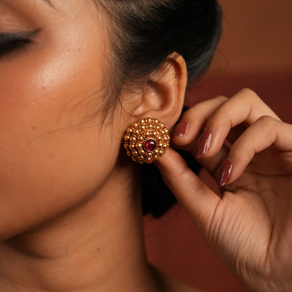 These gold-plated silver stud earrings showcase dainty coin-like motifs arranged in a graceful circular pattern. Inspired by vintage Kolhapuri tribal designs, they blend tradition with elegance, making them a timeless addition to any jewelry collection.