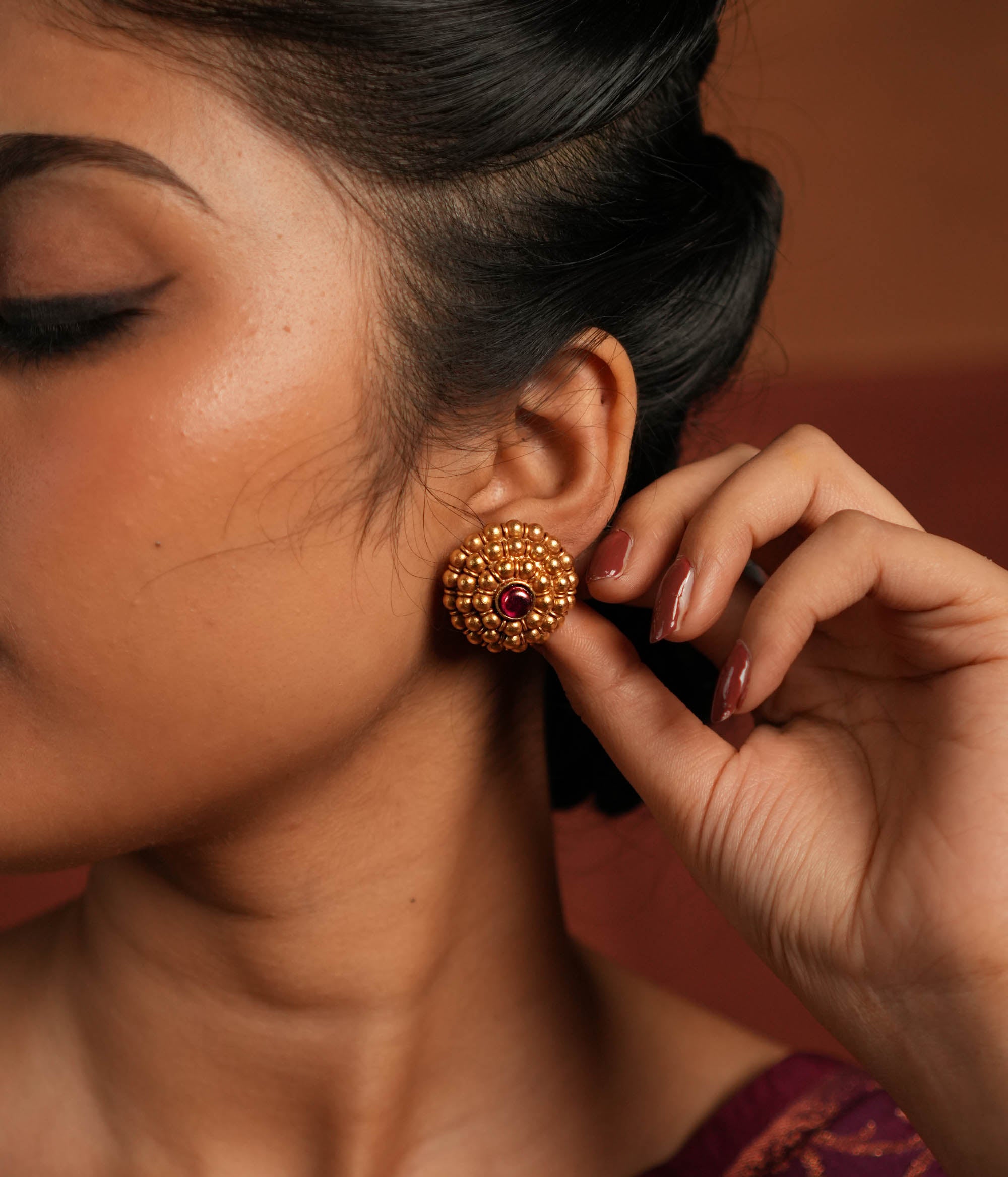 These gold-plated silver stud earrings showcase dainty coin-like motifs arranged in a graceful circular pattern. Inspired by vintage Kolhapuri tribal designs, they blend tradition with elegance, making them a timeless addition to any jewelry collection.