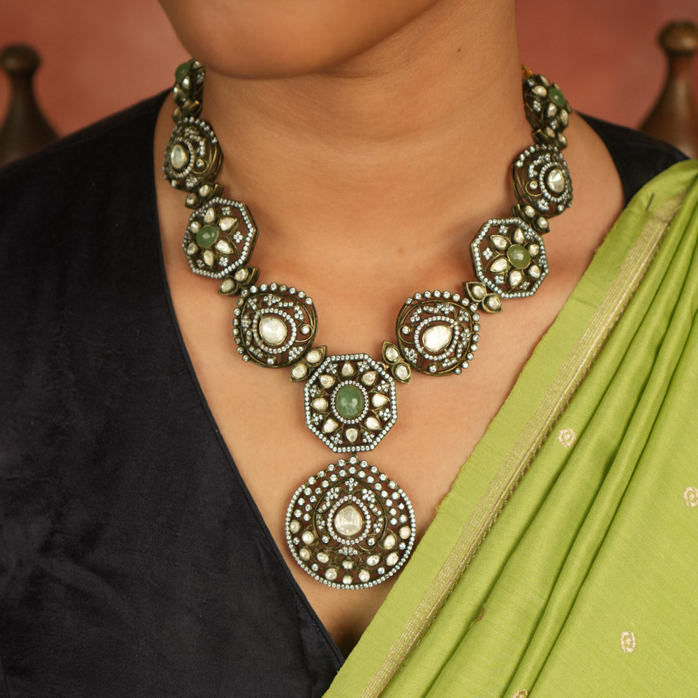 Victorian elegance reborn! This gold-plated necklace features round pendants adorned with polki, green gemstones, and CZ stones, leading to a striking emerald centerpiece. A radiant constellation of brilliance, echoing timeless luxury.