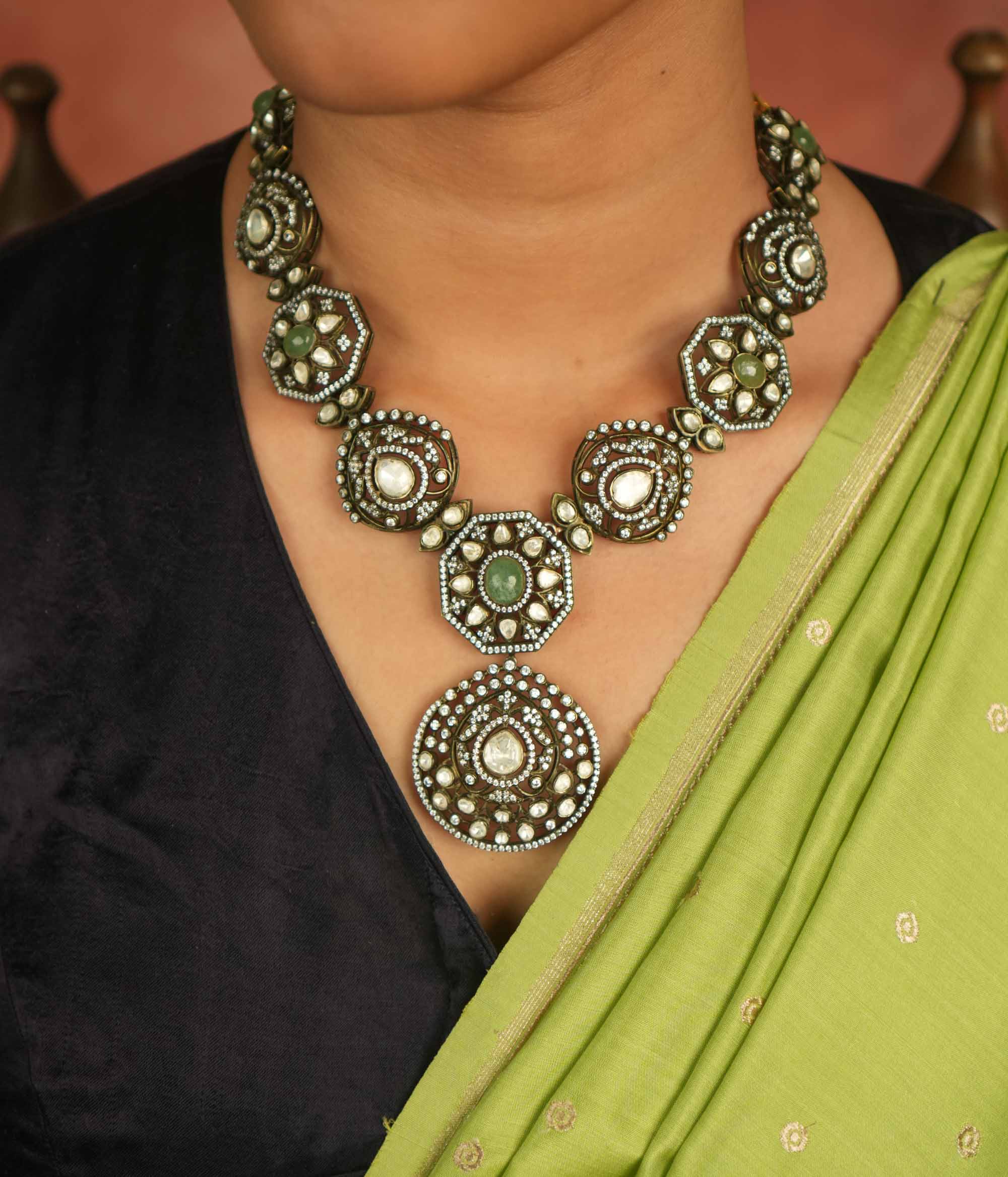 Victorian elegance reborn! This gold-plated necklace features round pendants adorned with polki, green gemstones, and CZ stones, leading to a striking emerald centerpiece. A radiant constellation of brilliance, echoing timeless luxury.