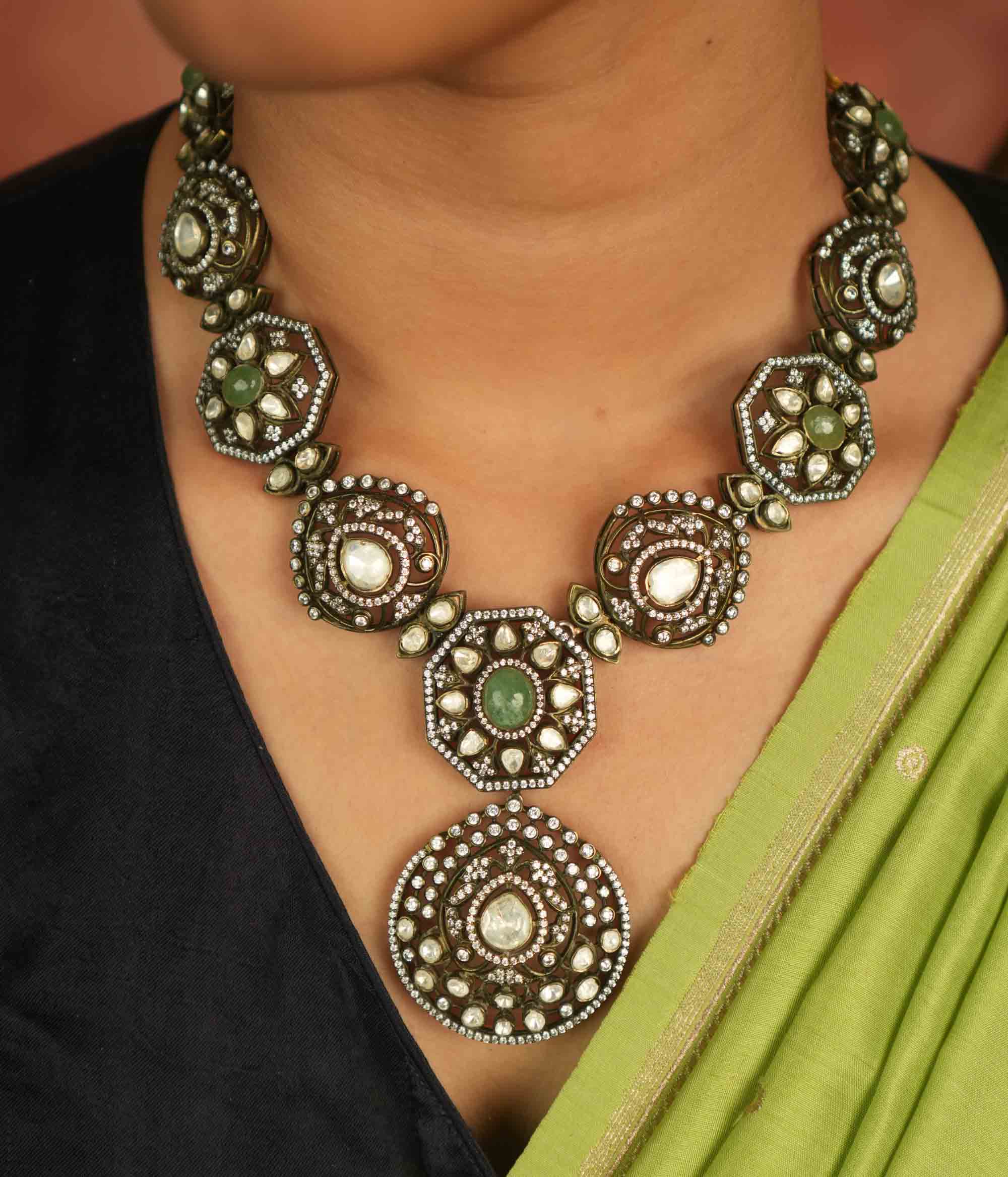 Victorian elegance reborn! This gold-plated necklace features round pendants adorned with polki, green gemstones, and CZ stones, leading to a striking emerald centerpiece. A radiant constellation of brilliance, echoing timeless luxury.
