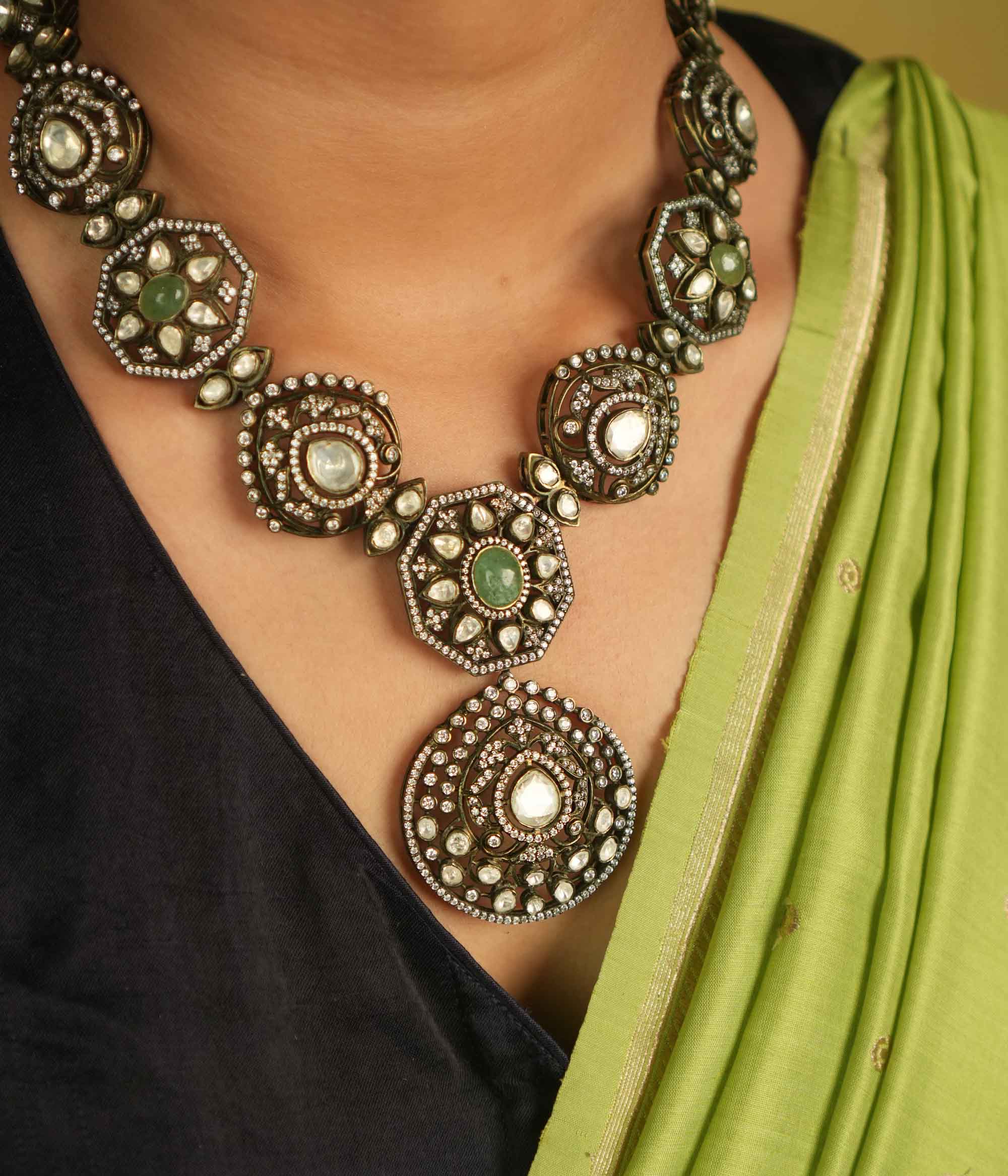 Victorian elegance reborn! This gold-plated necklace features round pendants adorned with polki, green gemstones, and CZ stones, leading to a striking emerald centerpiece. A radiant constellation of brilliance, echoing timeless luxury.
