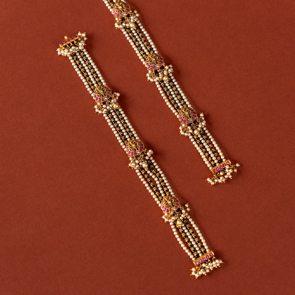 Handcrafted chain made of 92.5 sterling silver and 22 carat gold plating, featuring red and white Kundan stones and pearls. The design includes vibrant beads, intricate gold detailing, and delicate pearl drops, blending tradition with graceful elegance