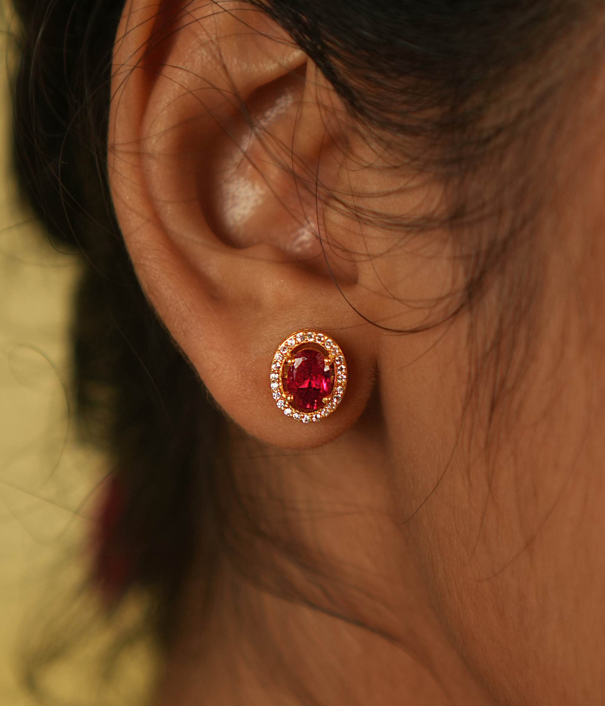 A delicate stud earring adorned with a captivating pink cut stone, encircled by shimmering Moissanite, exudes timeless charm and brilliance.