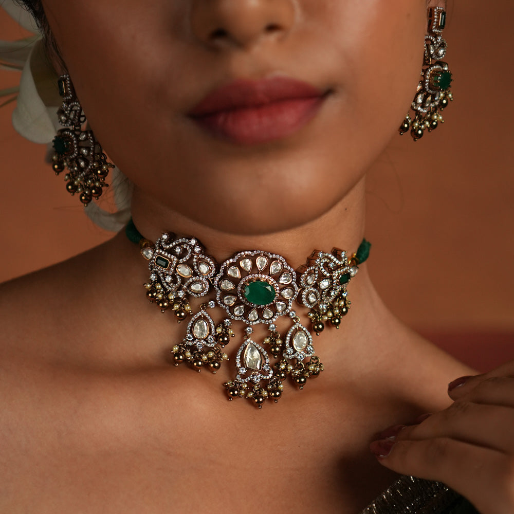 Victorian elegance reborn! This gold-plated silver choker features a striking green gemstone at its heart, surrounded by dazzling polki and CZ stones. Delicate pearl drops with golden beads enhance its timeless allure, whispering tales of a bygone era. A perfect blend of heritage and grace for the modern woman.