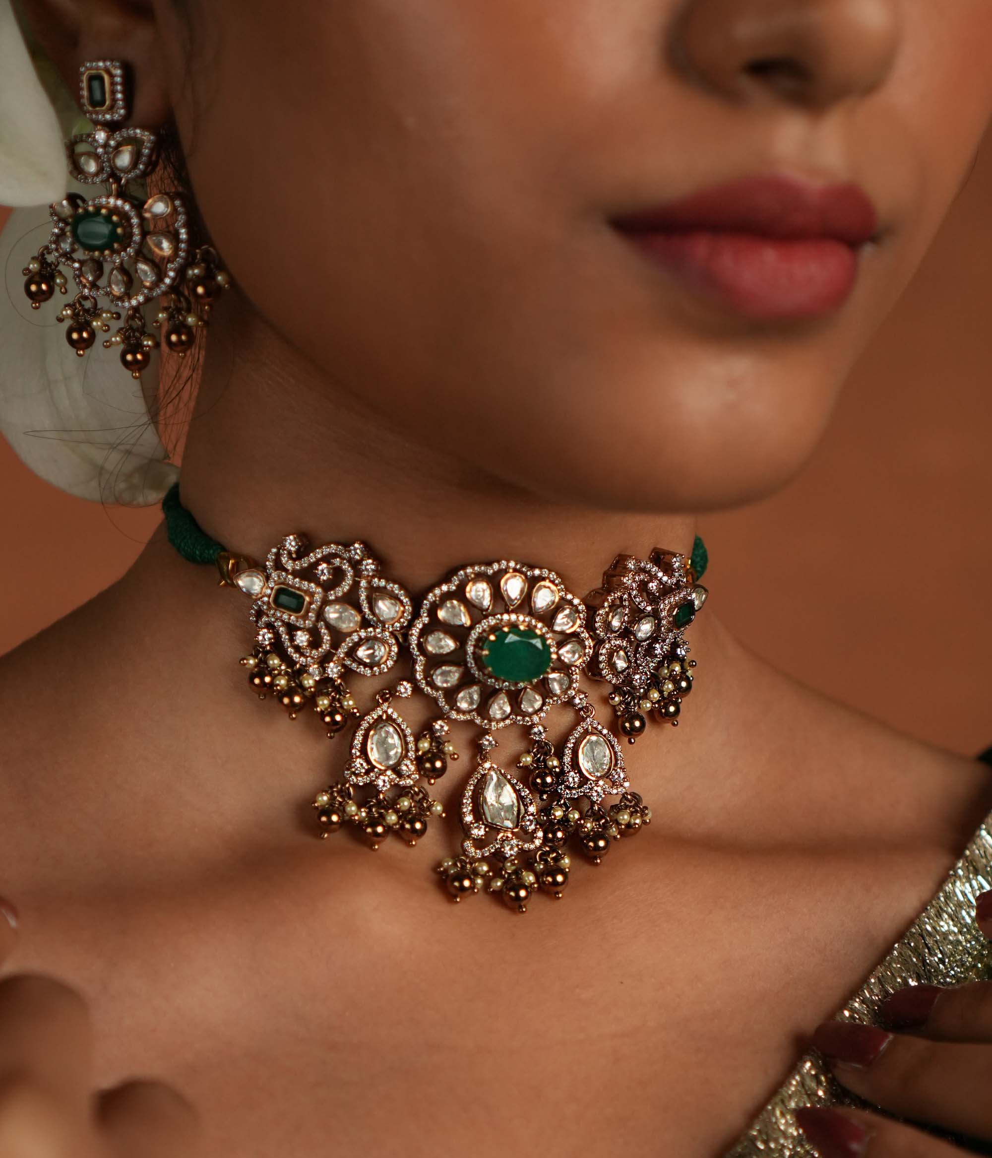 Victorian elegance reborn! This gold-plated silver choker features a striking green gemstone at its heart, surrounded by dazzling polki and CZ stones. Delicate pearl drops with golden beads enhance its timeless allure, whispering tales of a bygone era. A perfect blend of heritage and grace for the modern woman.