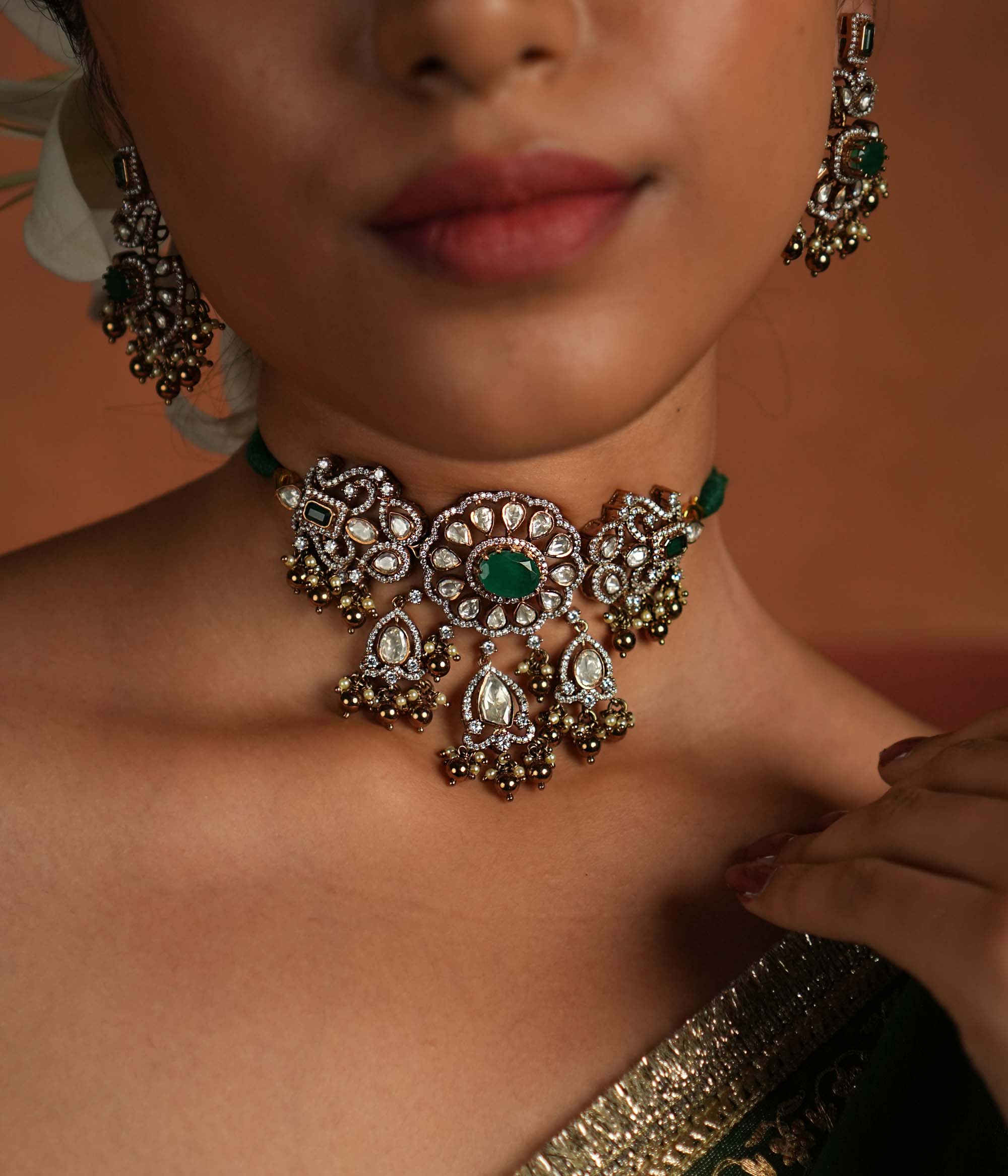 Victorian elegance reborn! This gold-plated silver choker features a striking green gemstone at its heart, surrounded by dazzling polki and CZ stones. Delicate pearl drops with golden beads enhance its timeless allure, whispering tales of a bygone era. A perfect blend of heritage and grace for the modern woman.
