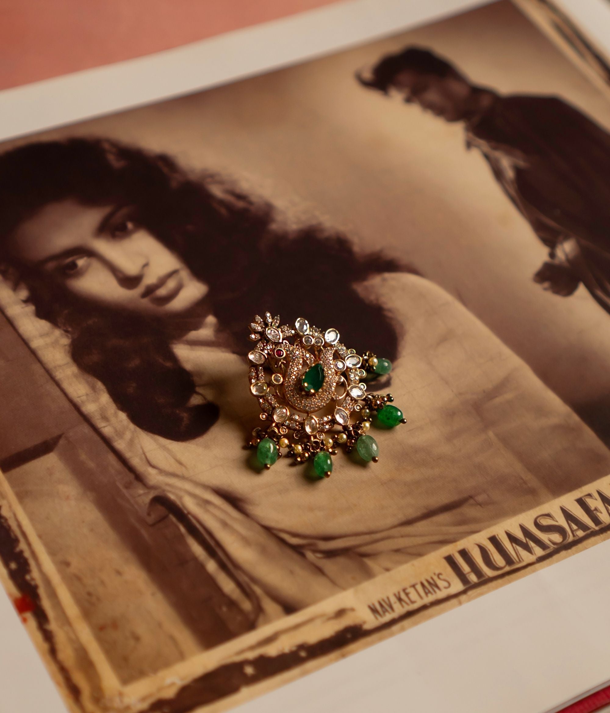 A mesmerizing gold-plated silver pendant featuring a majestic peacock at its center, intricately crafted with CZ stones and vibrant red cz stones. Encircling the peacock is a delicate arrangement of shimmering Polki stones, enhancing its regal allure. The pendant is further adorned with cascading drops of lush green strawberry quartz, adding a touch of elegance and charm. A perfect blend of tradition and craftsmanship, this pendant exudes timeless beauty.