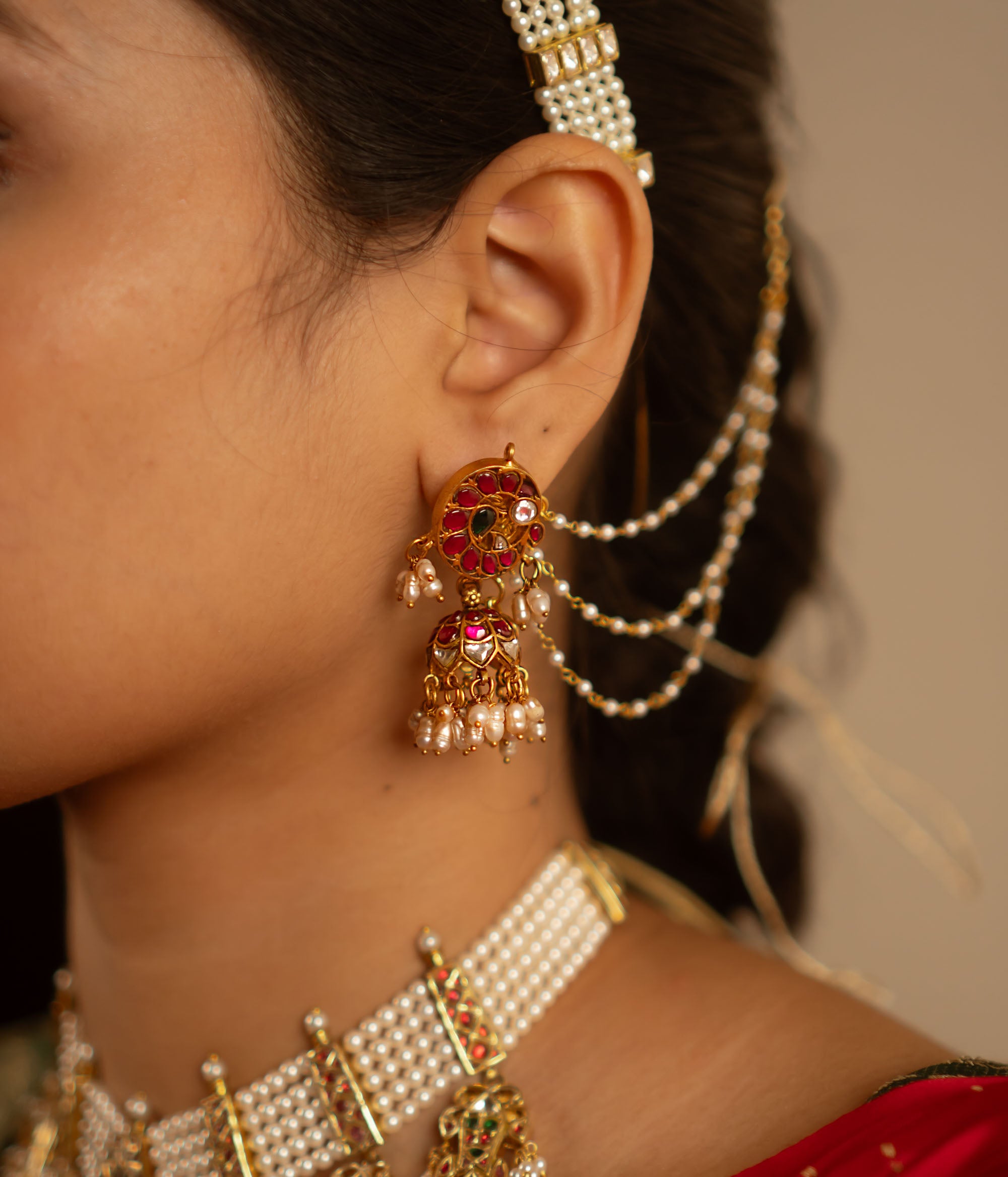 The Mogra earrings, designed in gold-plated silver and adorned with vibrant red, white, and green kundans along with delicate pearls, capture the essence of vintage elegance. A timeless jewel reminiscent of heirloom treasures.