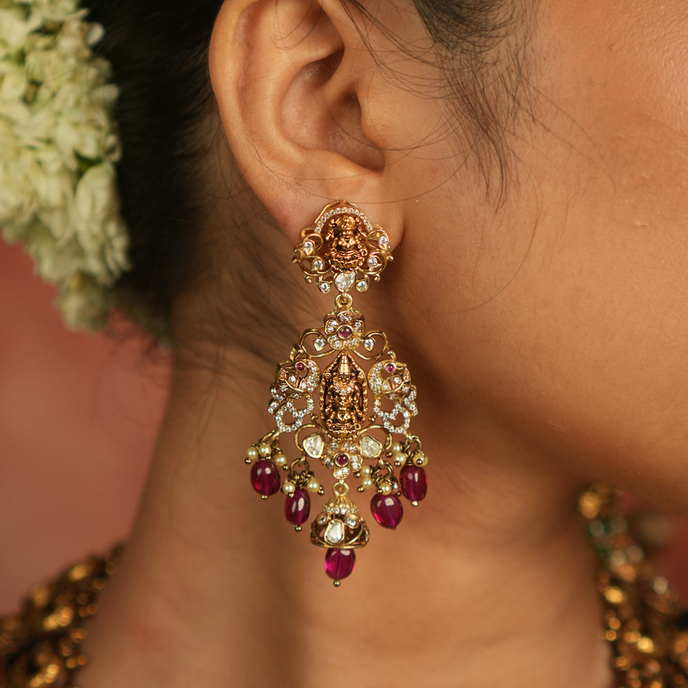 Celestial whispers reborn! These gold-plated Chandbali earrings showcase radiant red spinel stones, shimmering polki and CZ stones, adorned with green beads and delicate pearls. A timeless tribute to spiritual heritage and elegant craftsmanship.