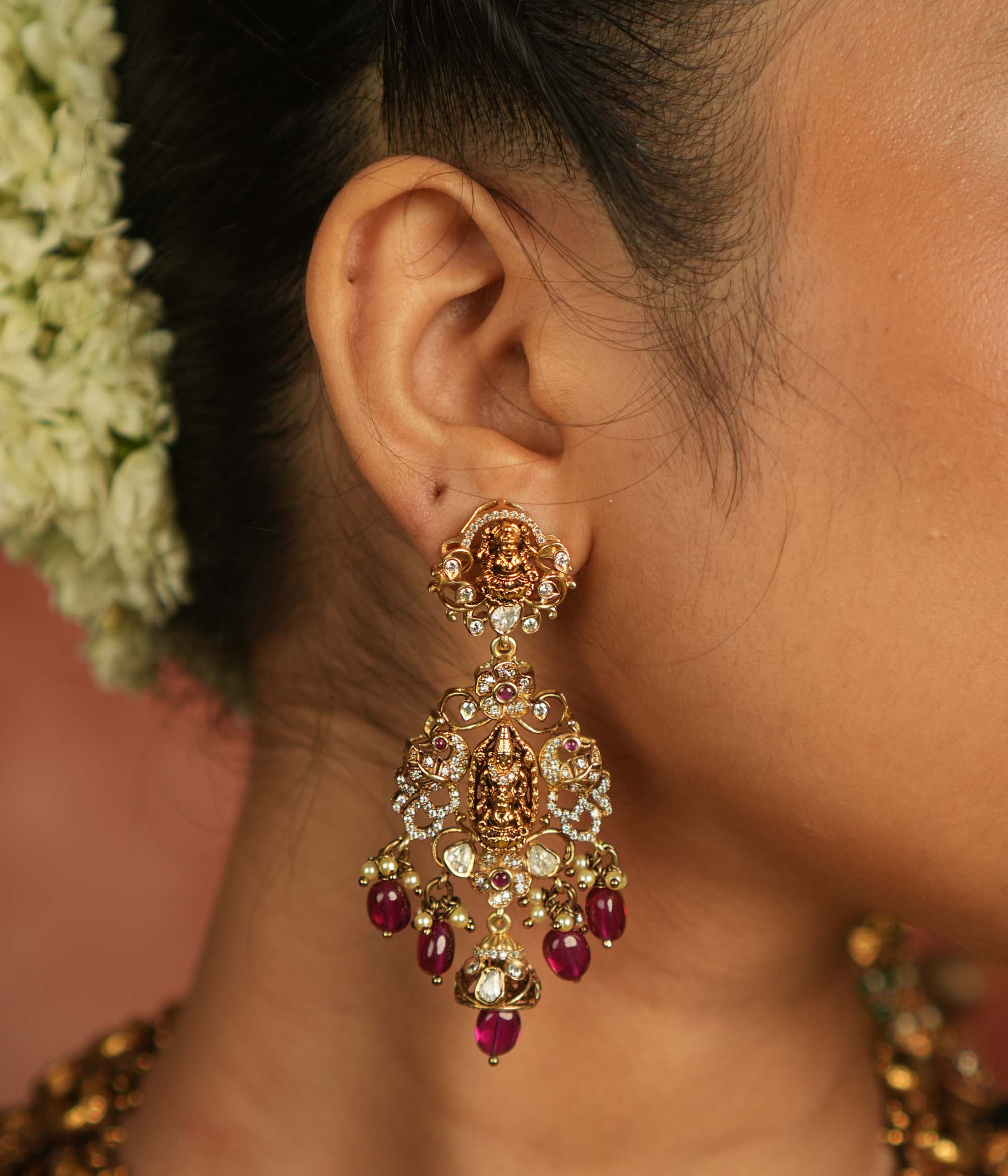 Celestial whispers reborn! These gold-plated Chandbali earrings showcase radiant red spinel stones, shimmering polki and CZ stones, adorned with green beads and delicate pearls. A timeless tribute to spiritual heritage and elegant craftsmanship.