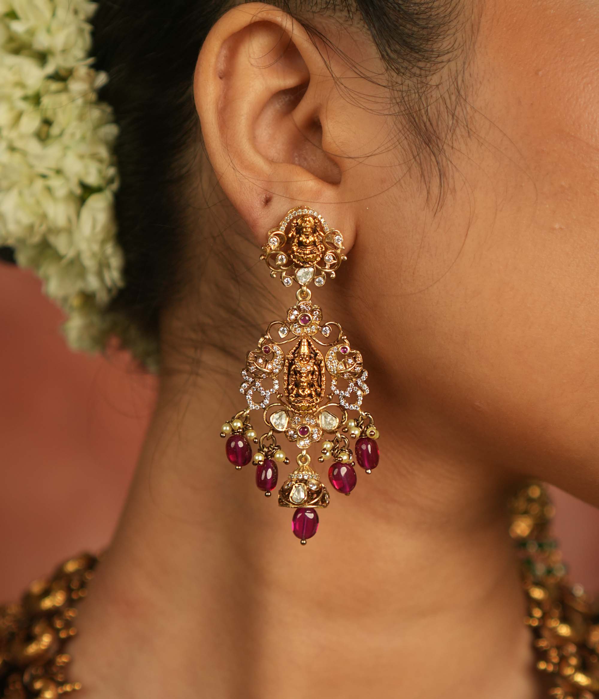 Celestial whispers reborn! These gold-plated Chandbali earrings showcase radiant red spinel stones, shimmering polki and CZ stones, adorned with green beads and delicate pearls. A timeless tribute to spiritual heritage and elegant craftsmanship.