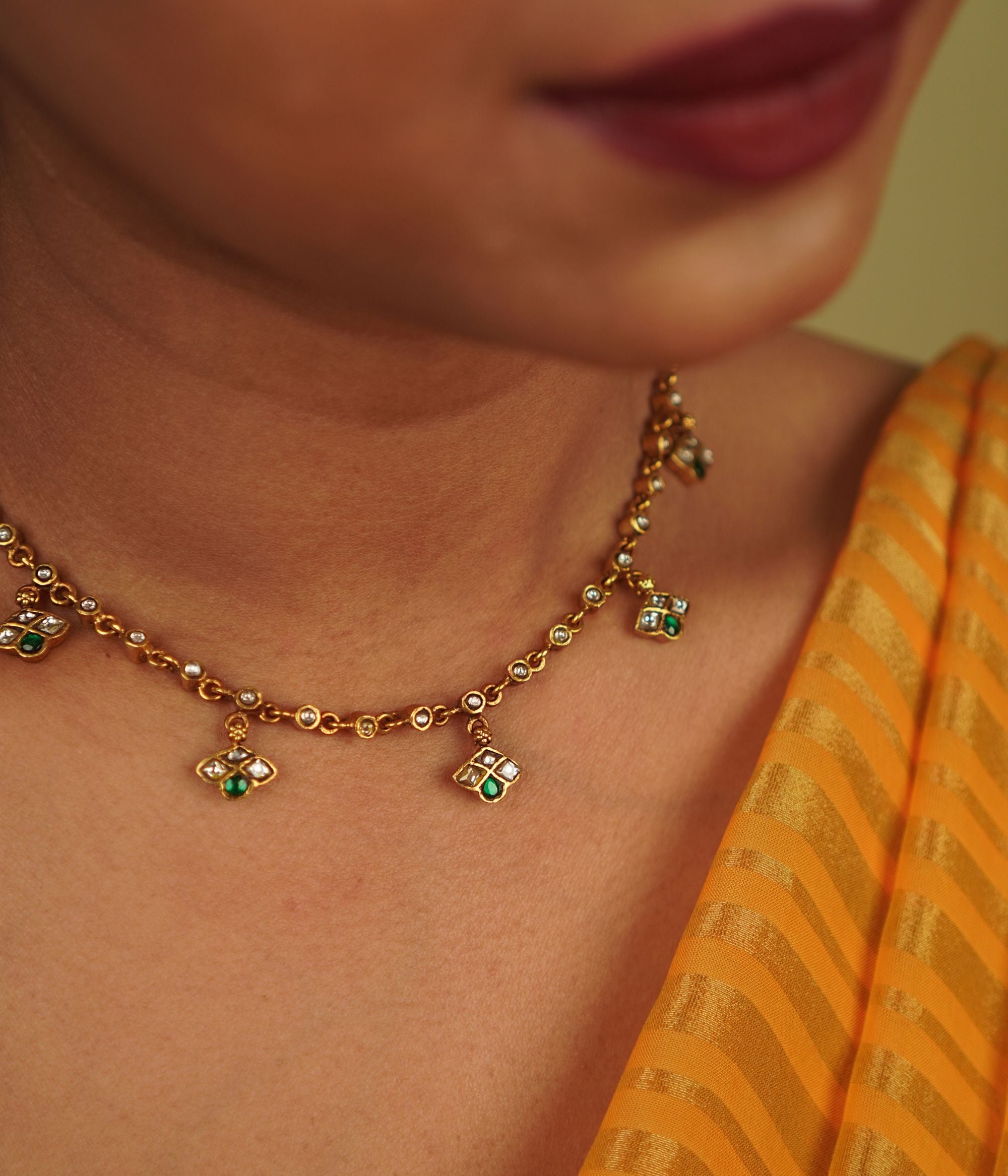 Mythri Necklace: A harmonious design of symmetrical units, this gold-plated silver piece showcases red and white Kundan stones, blending traditional craftsmanship with modern elegance, embodying Indian grace.
