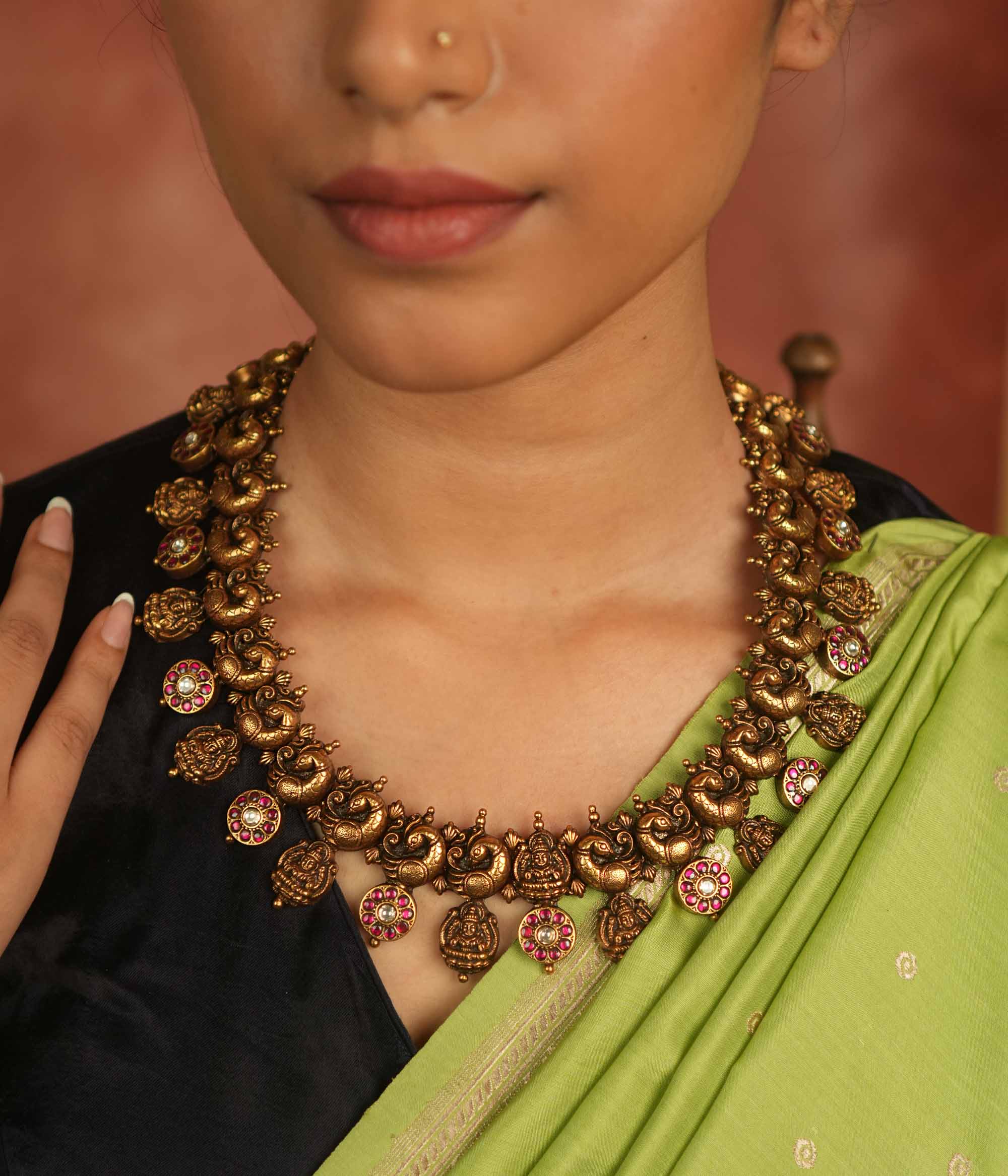 Regal whispers reborn in an antique gold-plated necklace, where floral and goddess motifs adorned with red and white kundan stones radiate timeless royal grace.