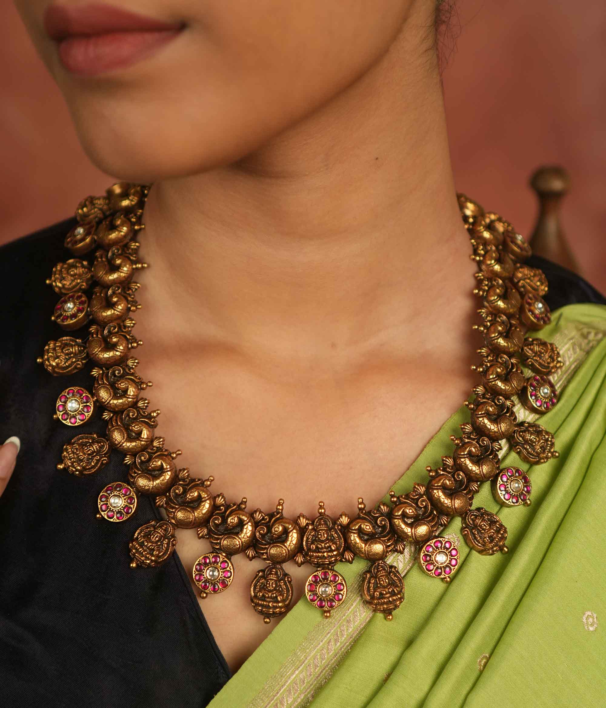 Regal whispers reborn in an antique gold-plated necklace, where floral and goddess motifs adorned with red and white kundan stones radiate timeless royal grace.