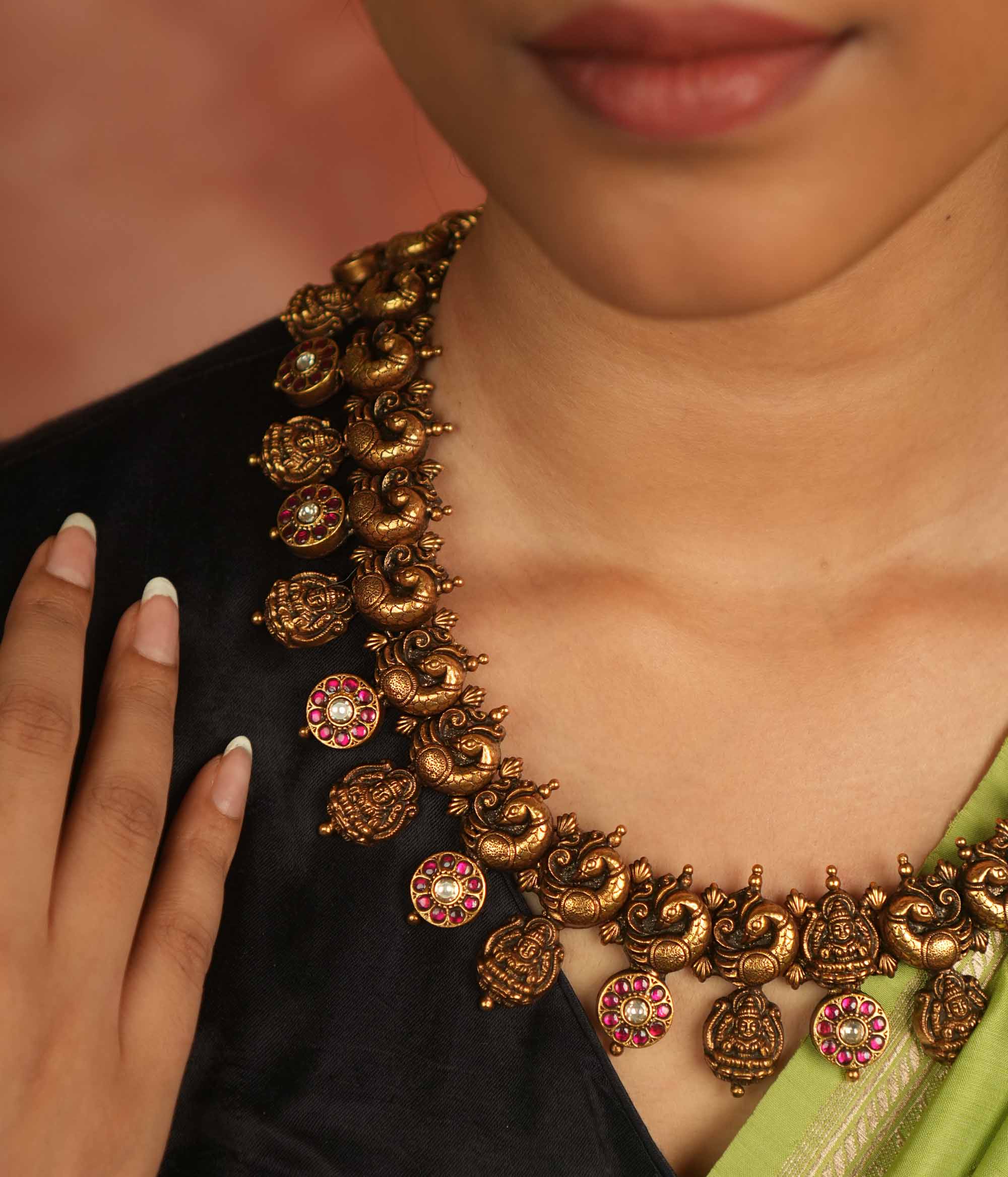 Regal whispers reborn in an antique gold-plated necklace, where floral and goddess motifs adorned with red and white kundan stones radiate timeless royal grace.