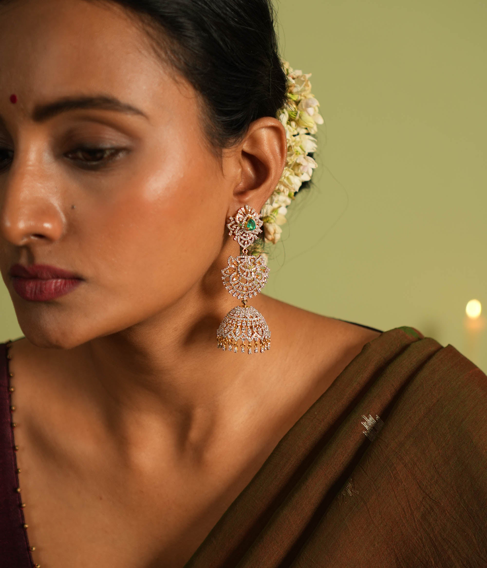 The Nakshatra Stone Jhumka features a mesmerizing green doublet stone and dazzling CZ accents, exuding timeless elegance with a radiant charm.