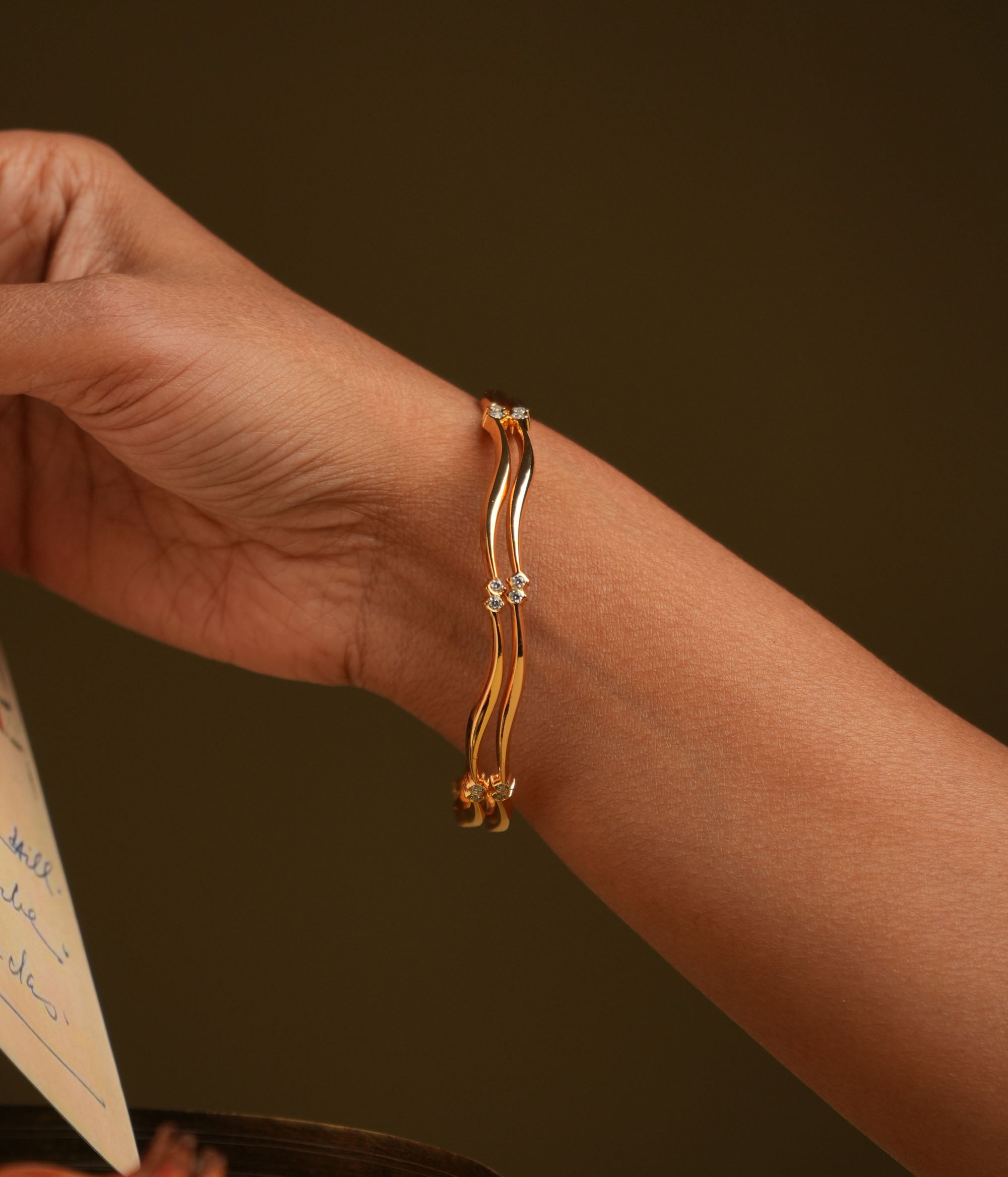 A minimal 92.5 sterling silver bangle with an insert closure, featuring a sleek, curved design centered with two delicate round Swarovski stones, embodying understated luxury and contemporary chic.