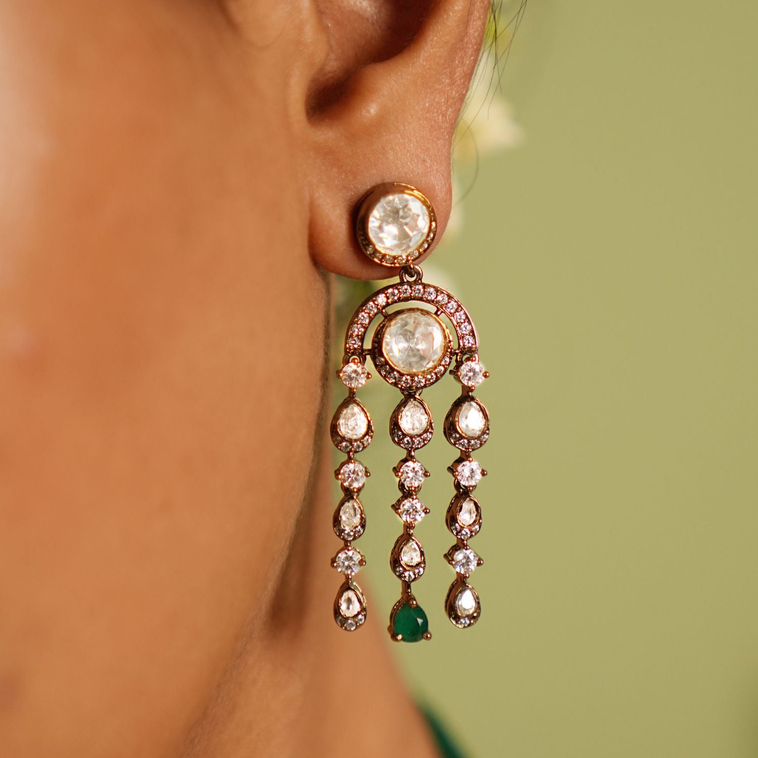 Echoes of a bygone era reborn! These gold-plated silver dangler earrings feature floral-shaped droplets adorned with Polki, CZ stones, and green spinal gems, cascading like delicate vines. A timeless blend of Victorian charm and graceful allure.