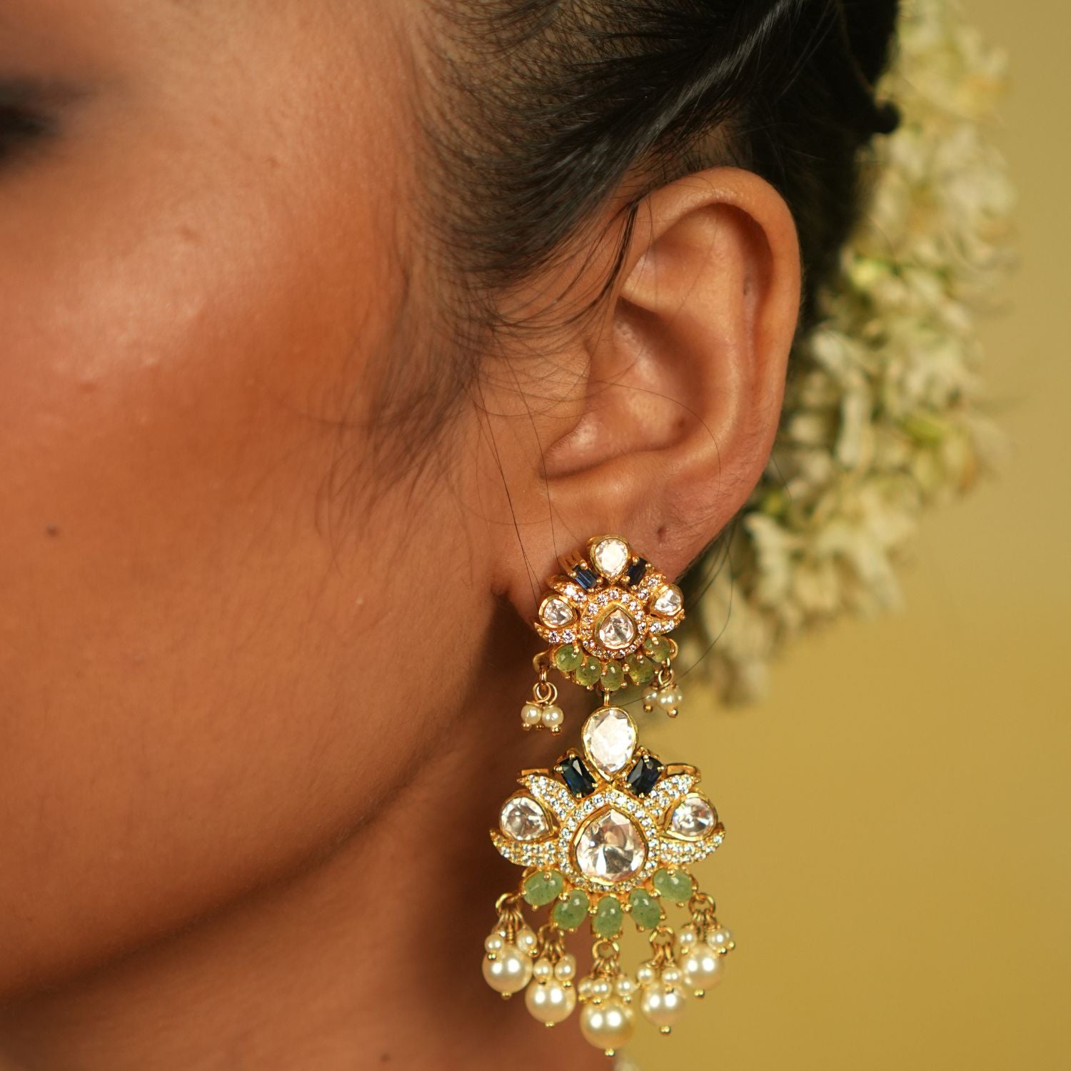 Pearl danglings sway gracefully, mirroring the serene ebb of lunar tides. These Polki-studded earrings are not just ornaments but a symphony of timeless elegance.