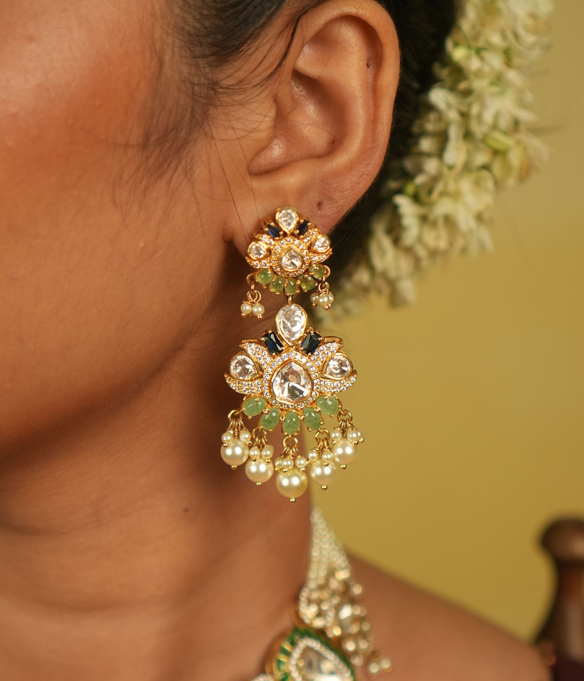 Pearl danglings sway gracefully, mirroring the serene ebb of lunar tides. These Polki-studded earrings are not just ornaments but a symphony of timeless elegance.