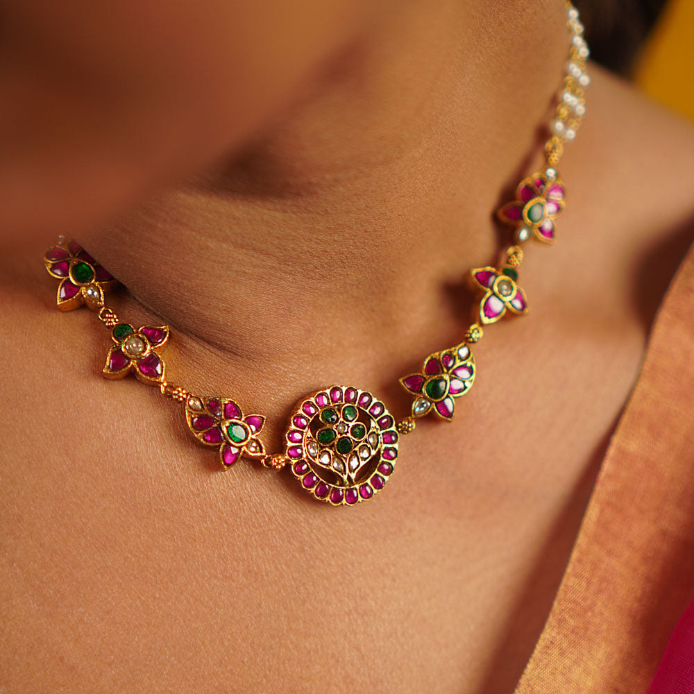 The Narcissus necklace, handcrafted in gold-plated silver, is adorned with vibrant red, white, and green kundans, complemented by delicate freshwater pearls. This vintage-inspired piece exudes a refined elegance, celebrating tradition with a touch of timeless charm.