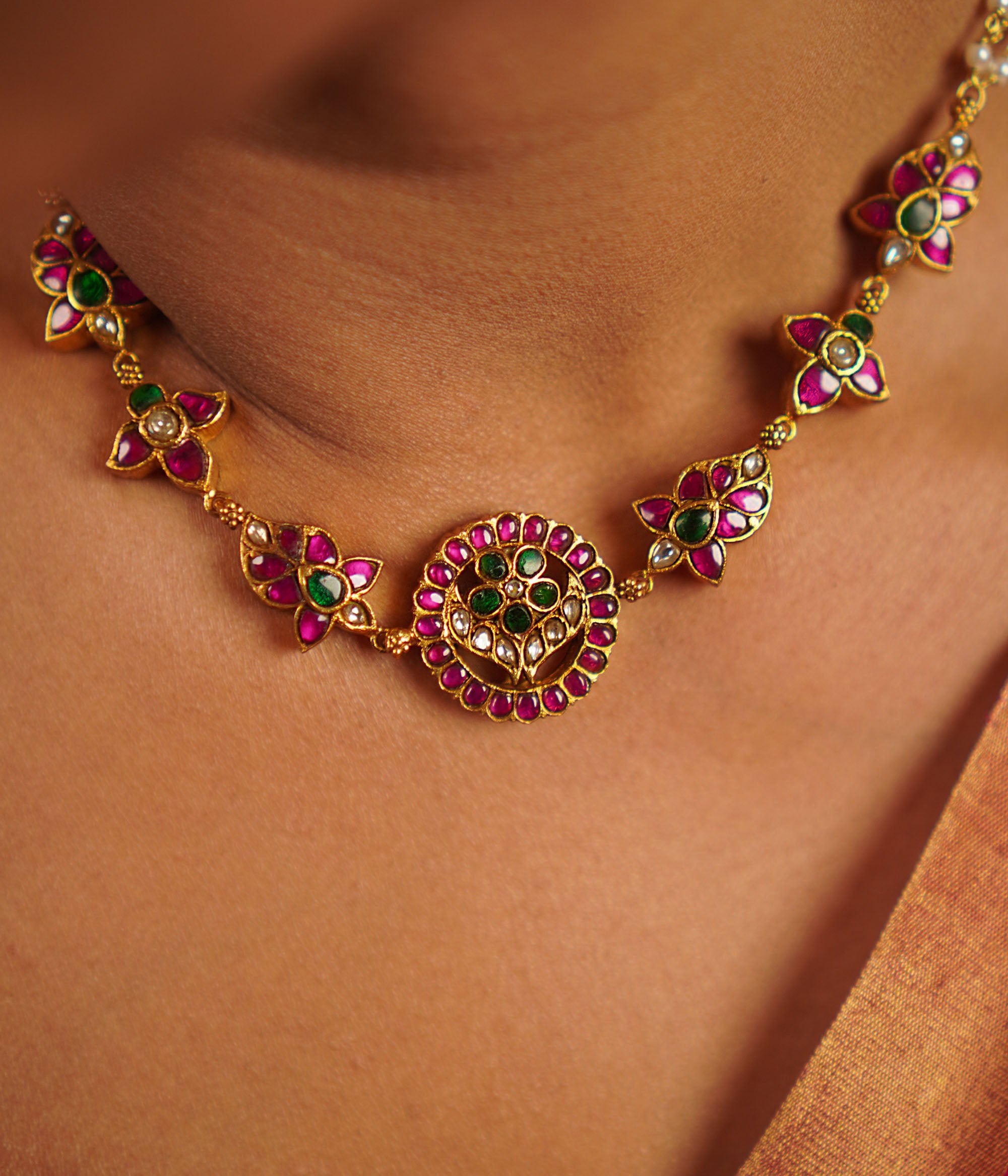 The Narcissus necklace, handcrafted in gold-plated silver, is adorned with vibrant red, white, and green kundans, complemented by delicate freshwater pearls. This vintage-inspired piece exudes a refined elegance, celebrating tradition with a touch of timeless charm.