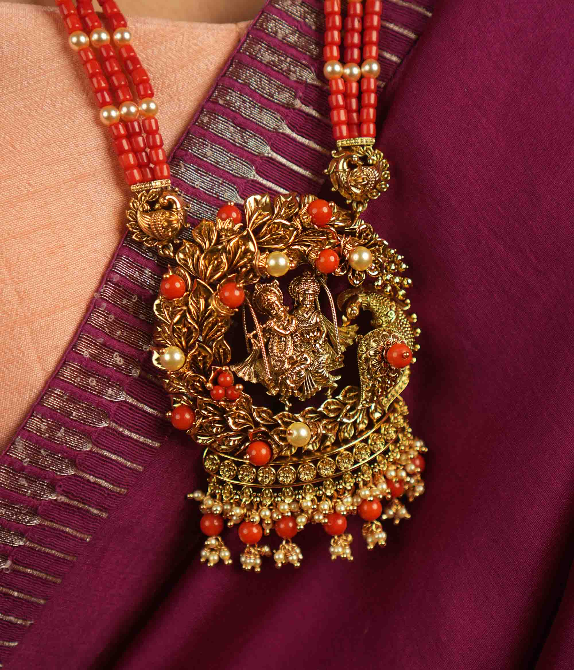 Eternal devotion reimagined! This gold-plated Radha Krishna necklace, set in a peacock-shaped frame, glows with rich red beads, symbolizing timeless love and divine grace.