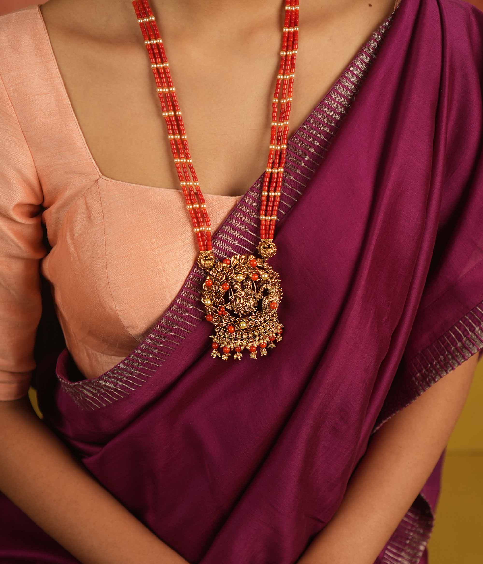 Eternal devotion reimagined! This gold-plated Radha Krishna necklace, set in a peacock-shaped frame, glows with rich red beads, symbolizing timeless love and divine grace.