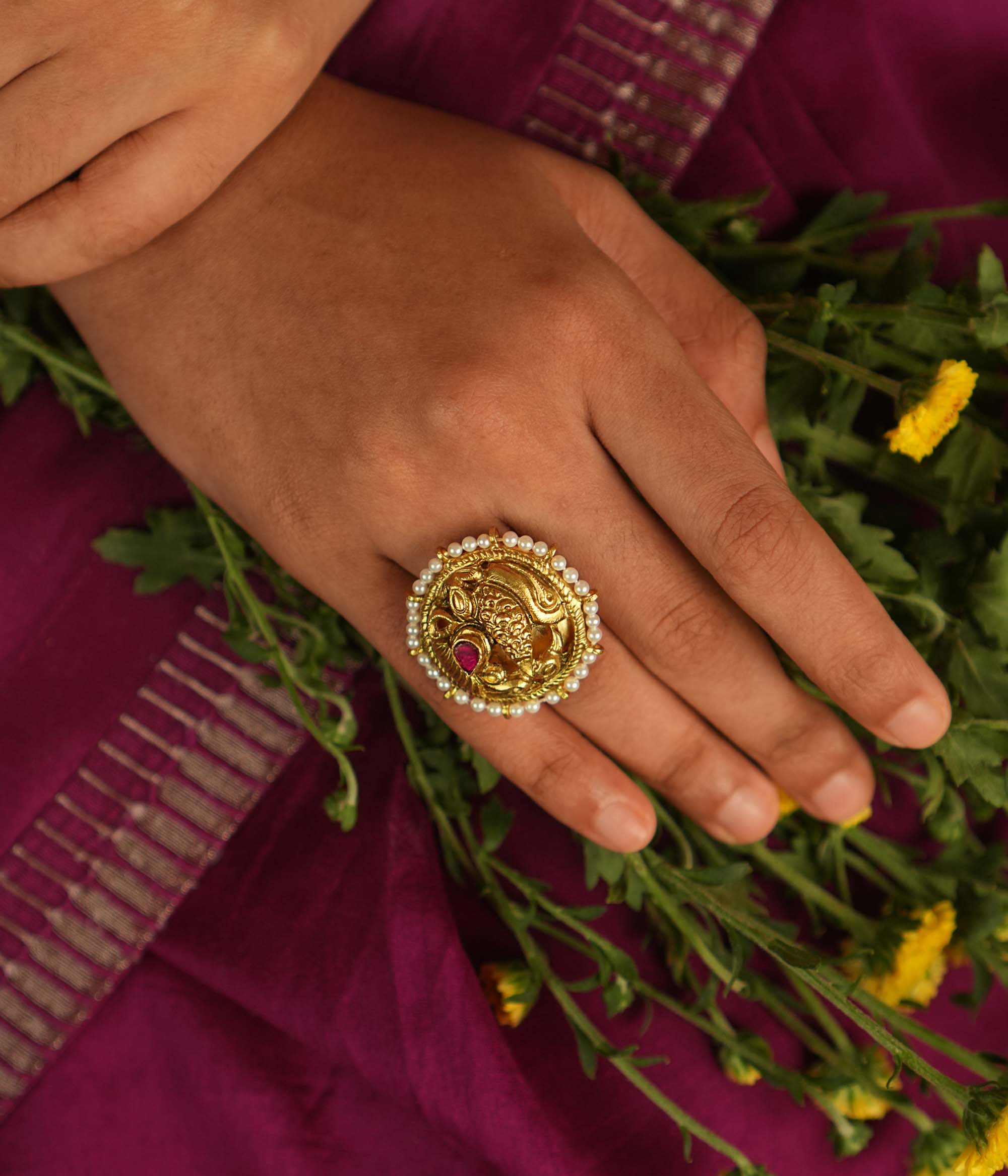 Adorn your finger with this exquisite gold-plated ring, featuring a captivating peacock motif, adorned with radiant red and white Kundan stones. The intricate feathers and Basra pearls add a touch of divine elegance, making this ring a timeless piece of craftsmanship.