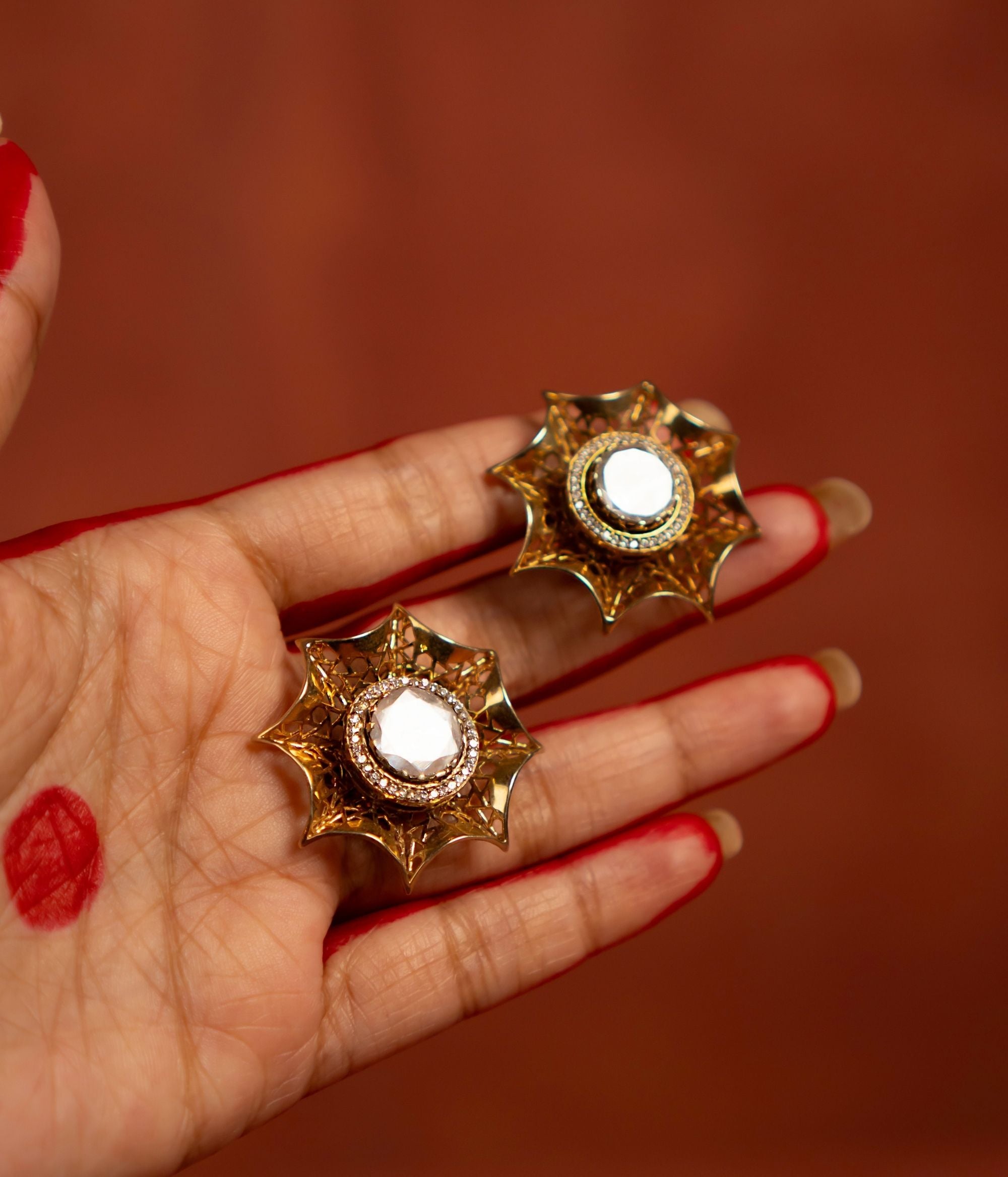 A stunning gold-plated silver stud earring featuring an intricate mesh web design. The centerpiece showcases a bold Moissanite Polki stone, elegantly surrounded by shimmering CZ stones, adding a touch of sophistication and timeless charm.