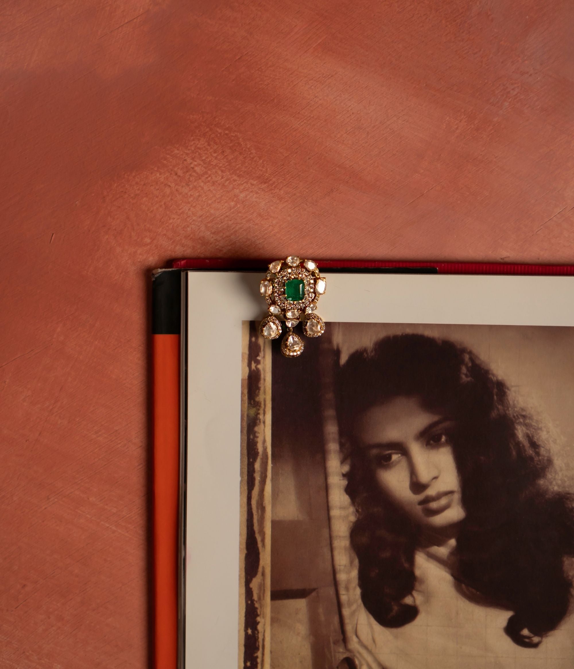 A stunning gold-plated silver pendant featuring a radiant green cut stone at its center, elegantly encircled by shimmering CZ stones and exquisite Polki stones. The design is further enhanced with three delicate Polki stone drops, each beautifully surrounded by CZ stones, adding a touch of sophistication and charm. This intricately crafted pendant exudes timeless elegance, making it a perfect statement piece for any occasion.