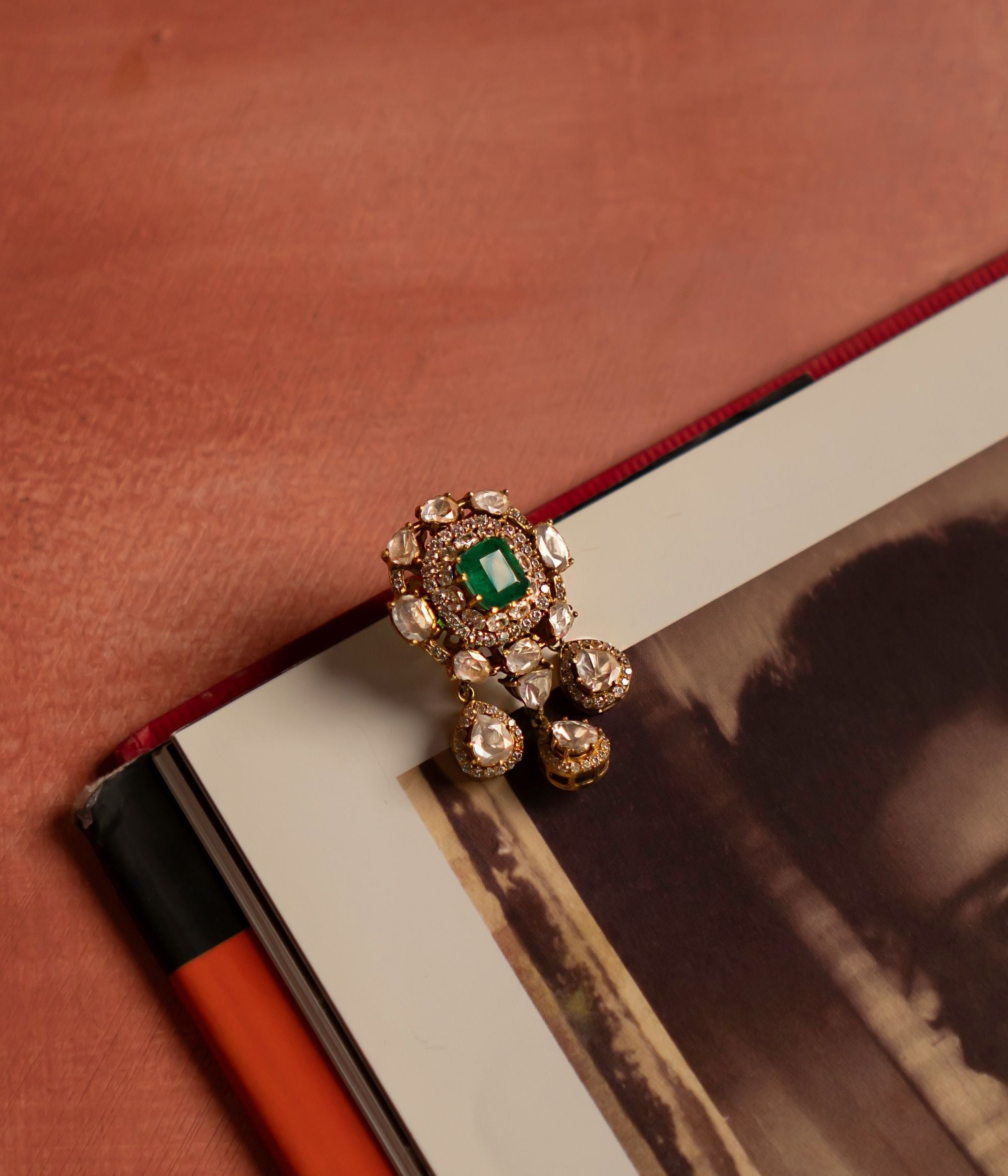 A stunning gold-plated silver pendant featuring a radiant green cut stone at its center, elegantly encircled by shimmering CZ stones and exquisite Polki stones. The design is further enhanced with three delicate Polki stone drops, each beautifully surrounded by CZ stones, adding a touch of sophistication and charm. This intricately crafted pendant exudes timeless elegance, making it a perfect statement piece for any occasion.