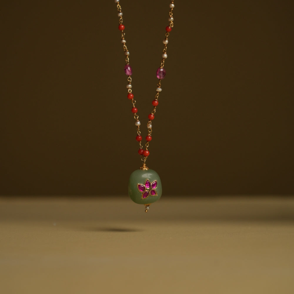 A minimal 92.5 sterling silver necklace featuring a natural green stone intricately engraved with pink Kundan meenakari, inspired by Rajput design.
