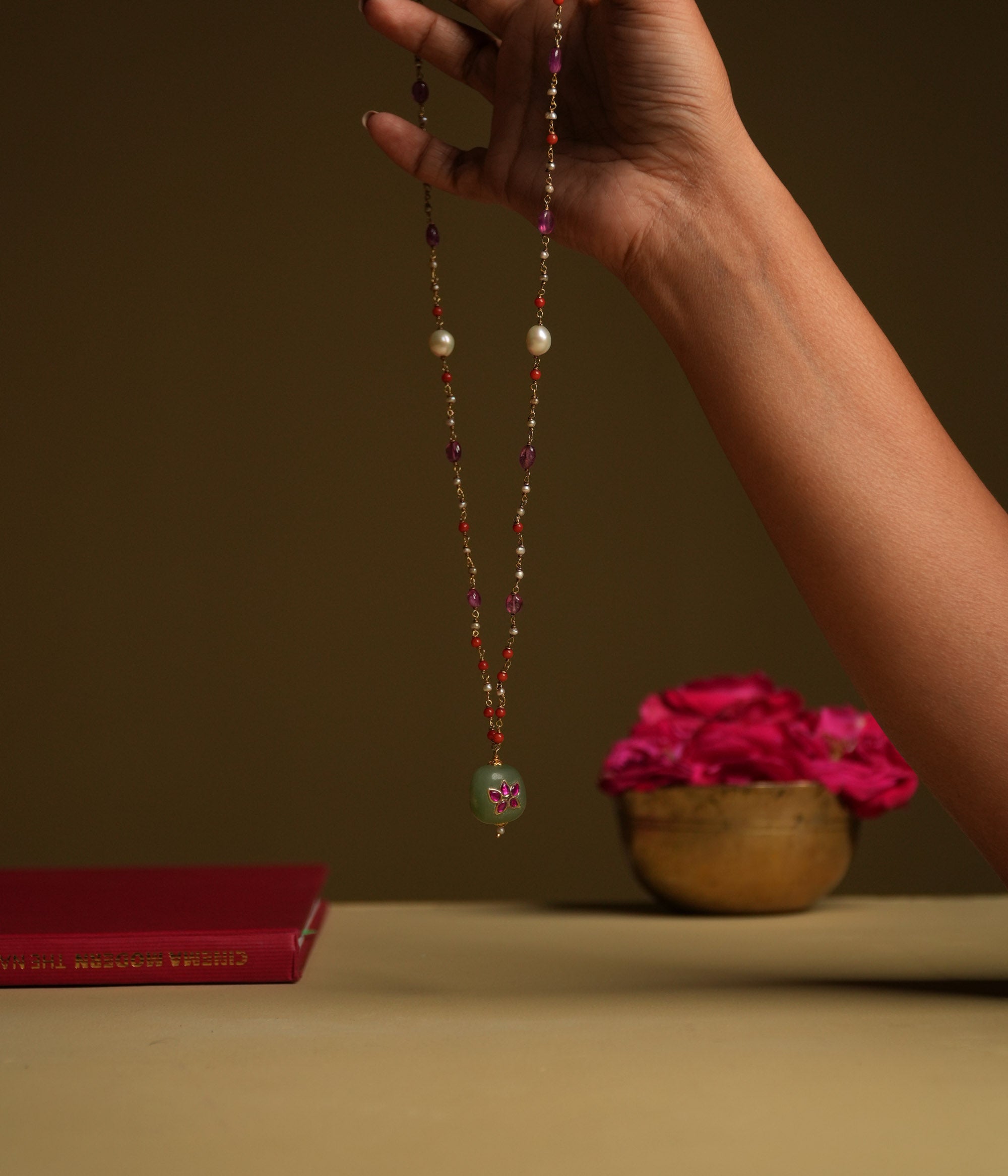 A minimal 92.5 sterling silver necklace featuring a natural green stone intricately engraved with pink Kundan meenakari, inspired by Rajput design.