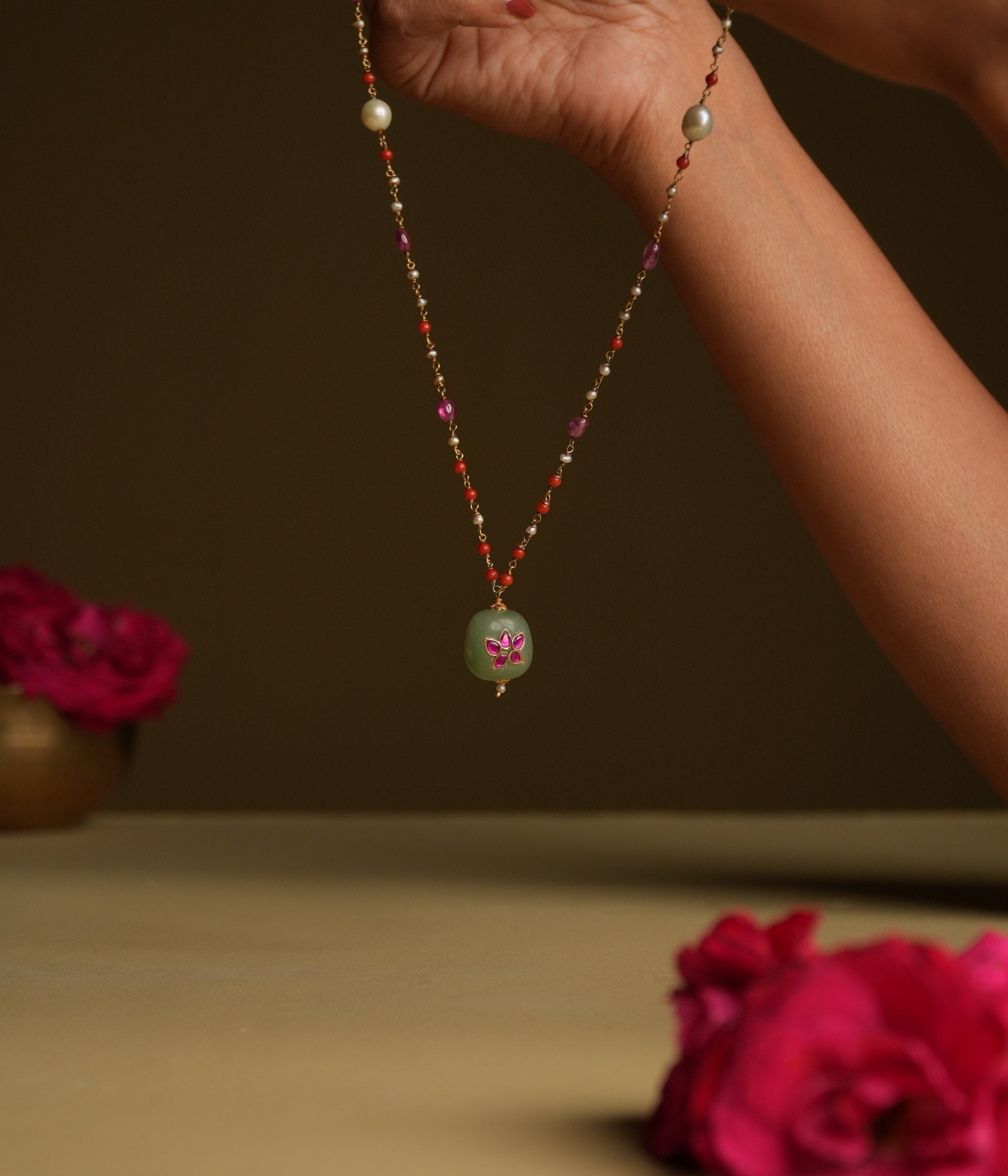 A minimal 92.5 sterling silver necklace featuring a natural green stone intricately engraved with pink Kundan meenakari, inspired by Rajput design.