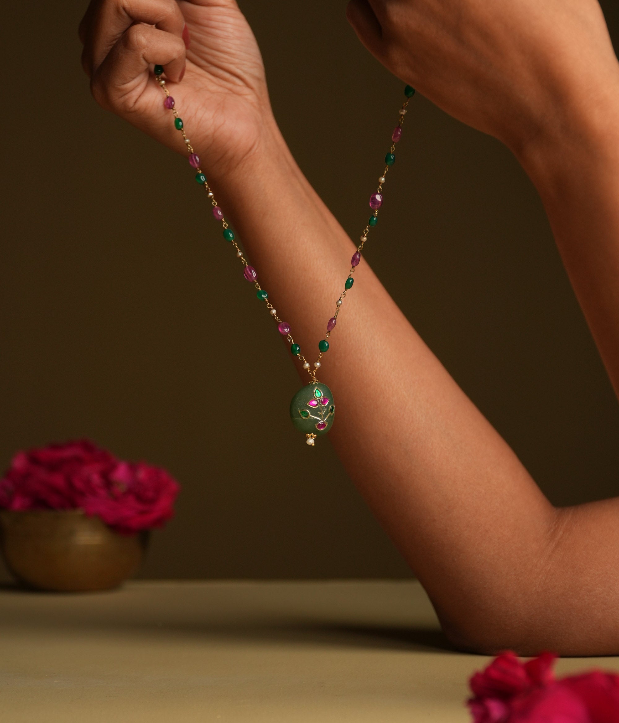A 92.5 sterling silver necklace featuring a bold green natural stone pendant, adorned with intricate Meenakari Kundan accents in rich purple hues, inspired by vintage Rajput techniques.
