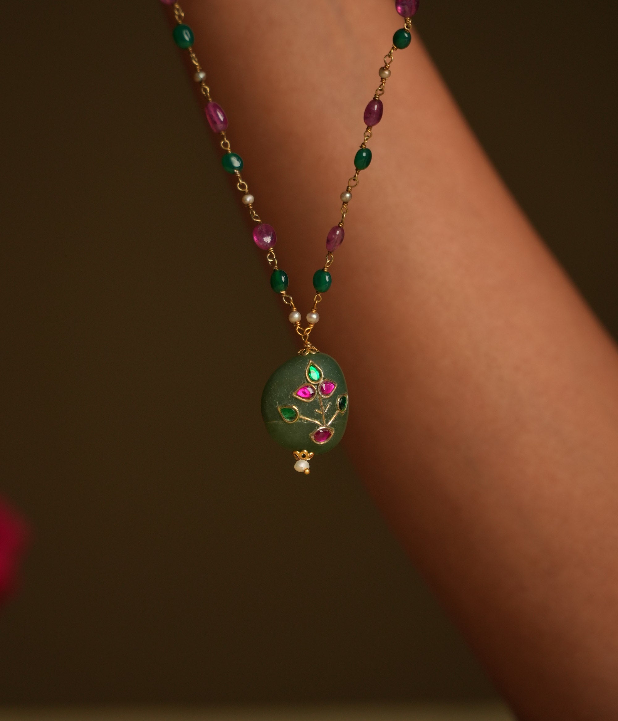A 92.5 sterling silver necklace featuring a bold green natural stone pendant, adorned with intricate Meenakari Kundan accents in rich purple hues, inspired by vintage Rajput techniques.