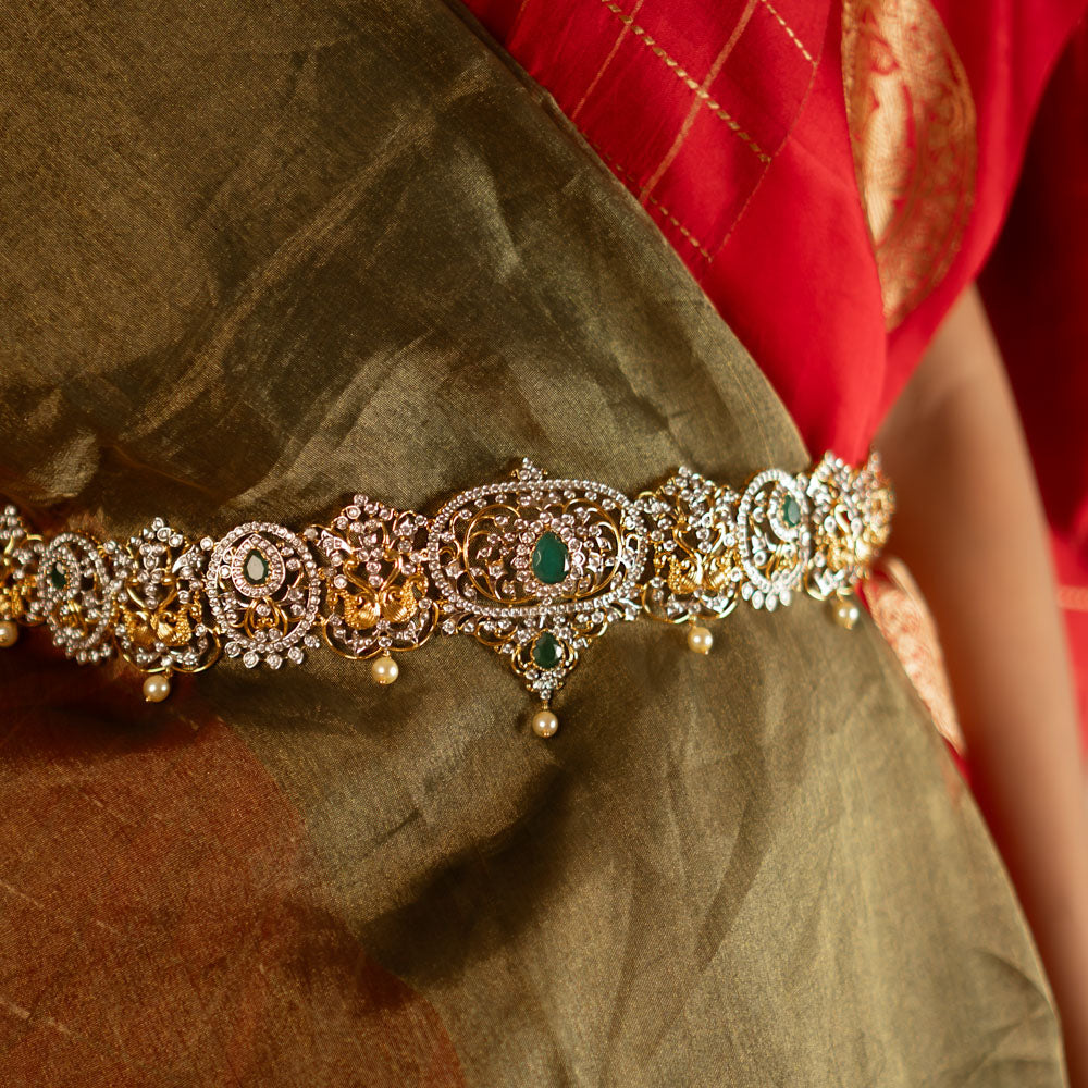 This hip belt is adorned with radiant green spinel stones, lustrous pearls, and sparkling CZ stones. Designed in a Victorian-inspired floral pattern, it showcases a mesmerizing blend of kundans and moissanite, exuding timeless elegance.