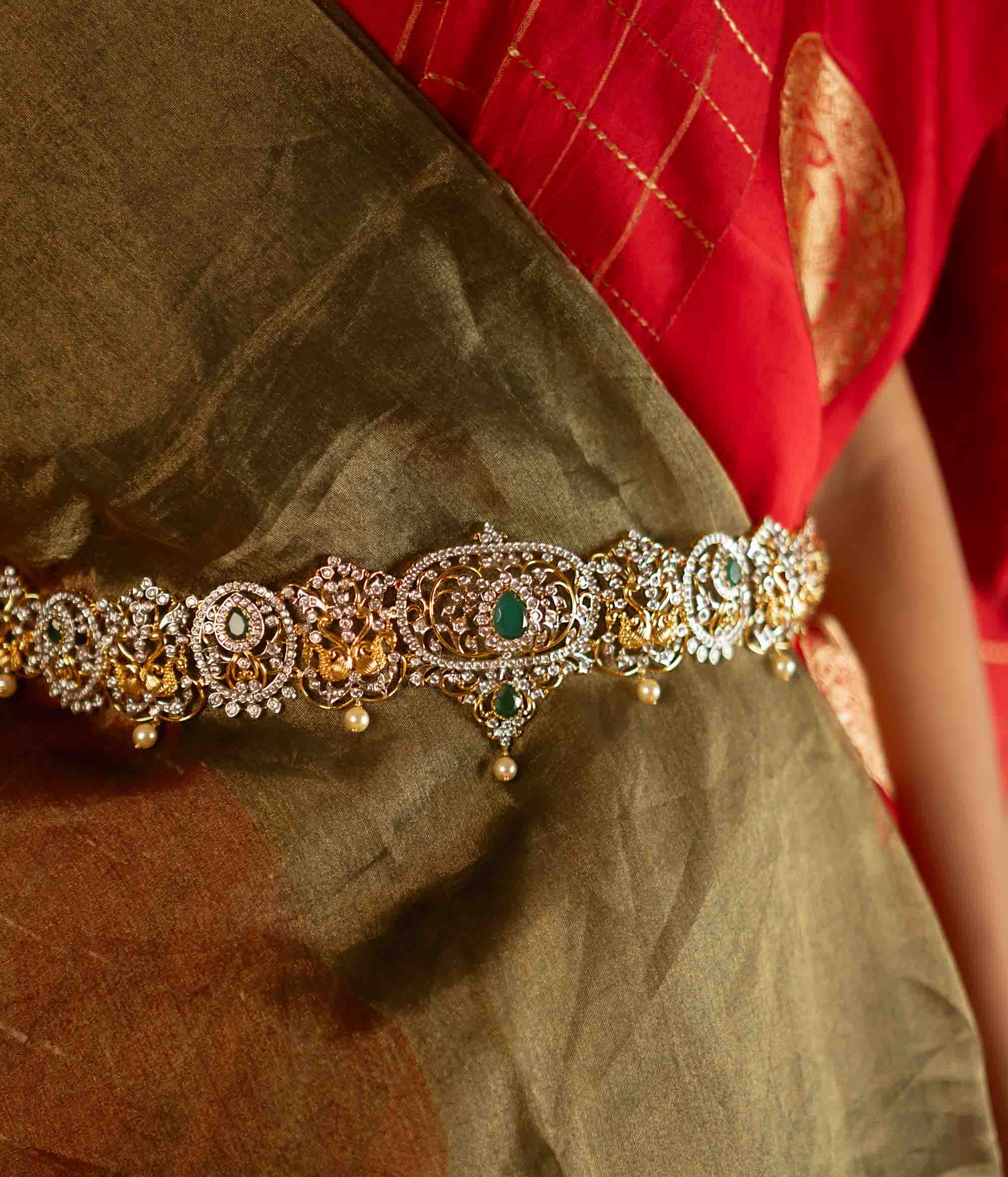 This hip belt is adorned with radiant green spinel stones, lustrous pearls, and sparkling CZ stones. Designed in a Victorian-inspired floral pattern, it showcases a mesmerizing blend of kundans and moissanite, exuding timeless elegance.