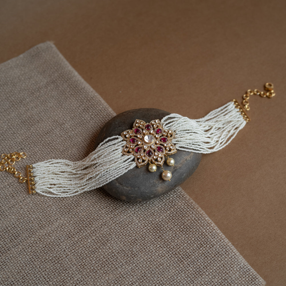 A divine blossom of Polki and pearls, kissed by red starlight, gracing your neck with celestial charm.